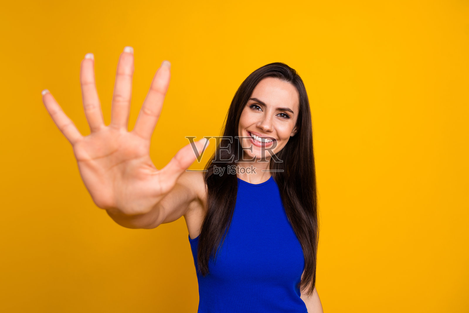 照片中，一个兴高采烈的女人穿着蓝色上衣，露出五个手指，背景是黄色照片摄影图片