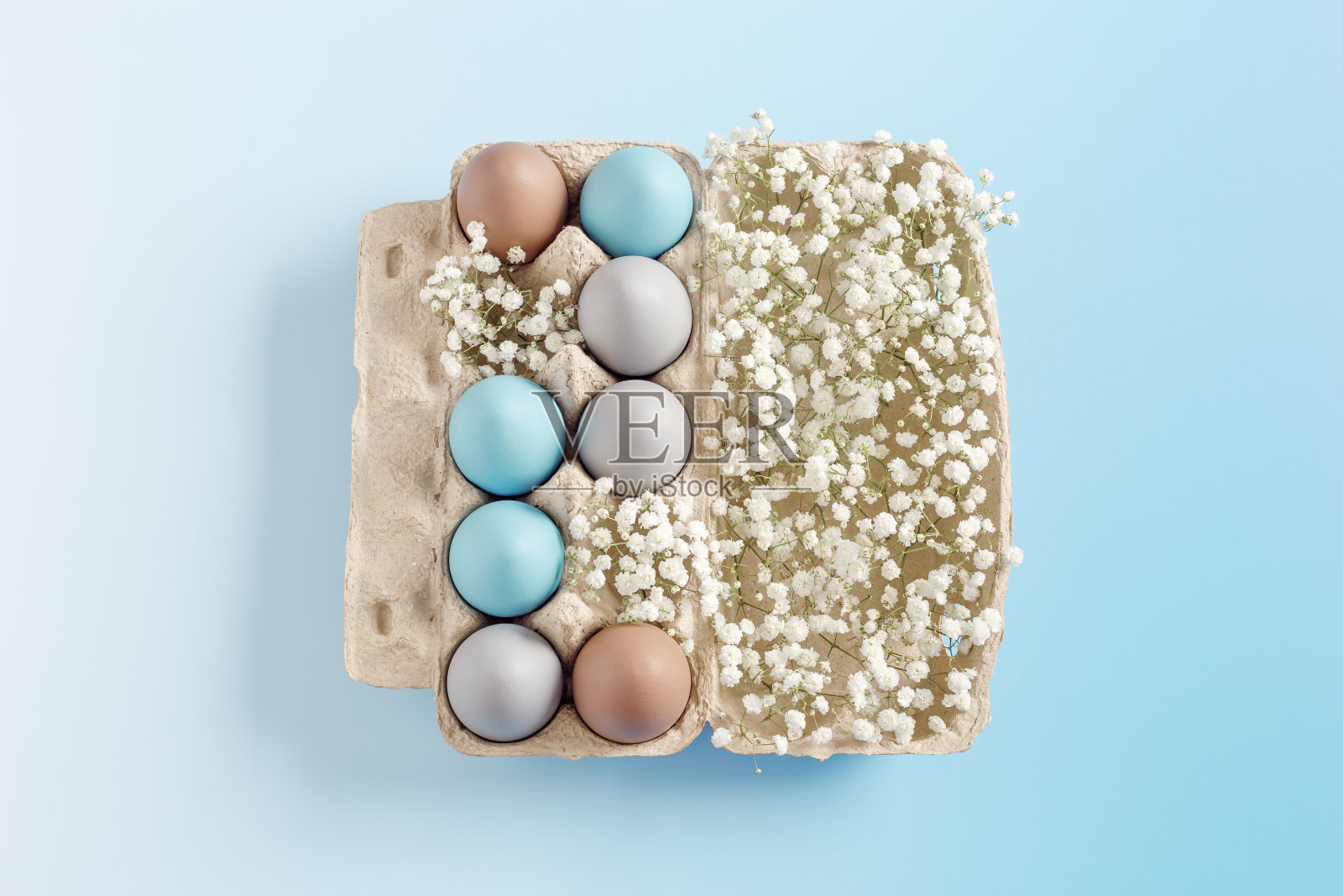 粉彩复活节彩蛋与白色的花朵在纸箱上蓝色的背景，顶视图鸡蛋画天空蓝色，米色。复活节庆祝概念。节日美食，极简静物节日照片摄影图片