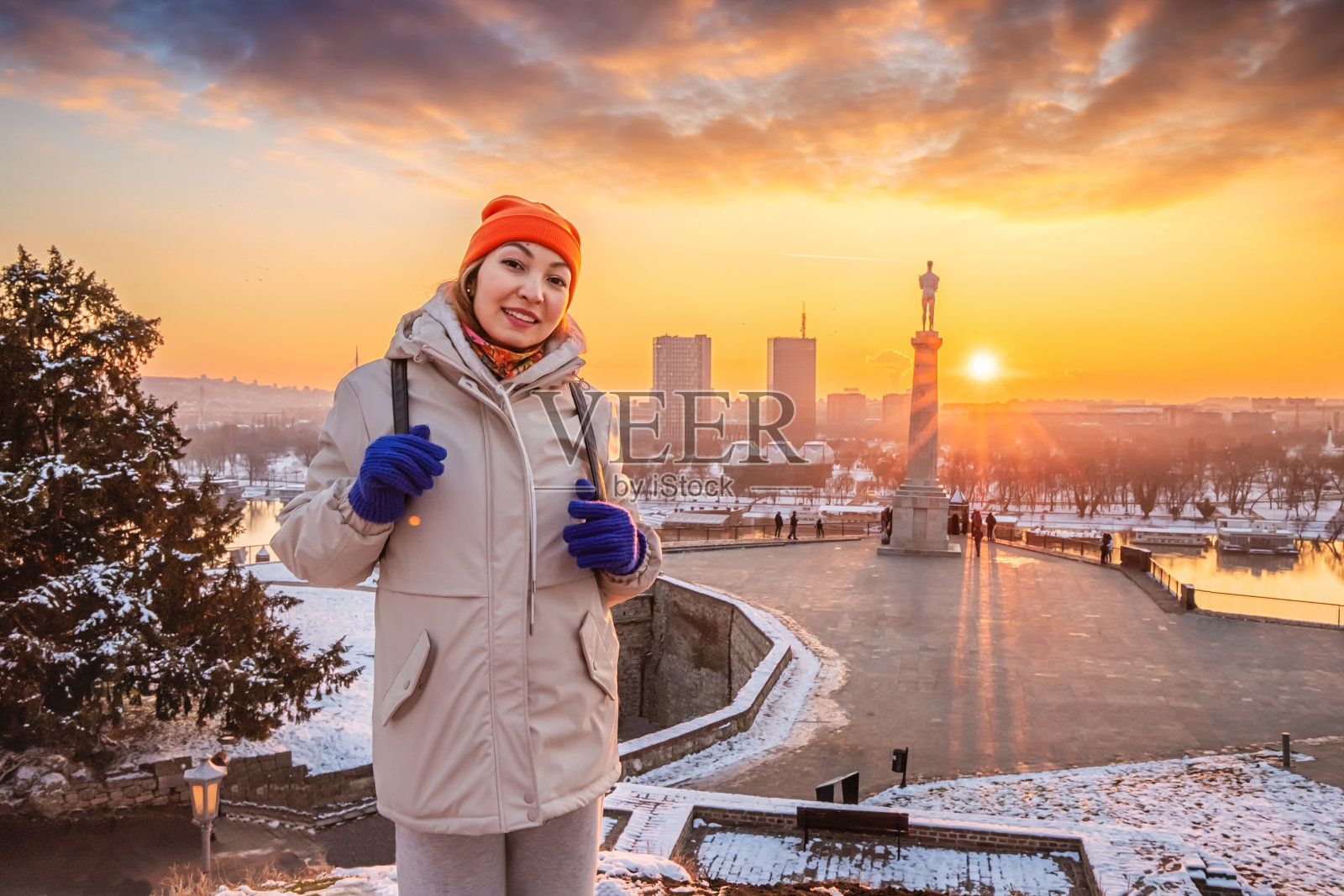 在白雪皑皑的卡莱梅格丹，一位女士站在雄伟的建筑中，这是贝尔格莱德历史堡垒永恒魅力的缩影。照片摄影图片