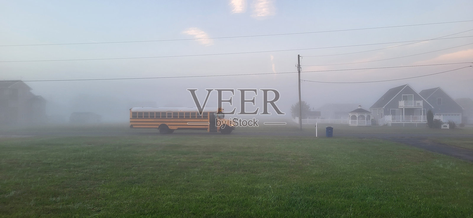 雾蒙蒙的早晨，有校车在乡间小路上照片摄影图片