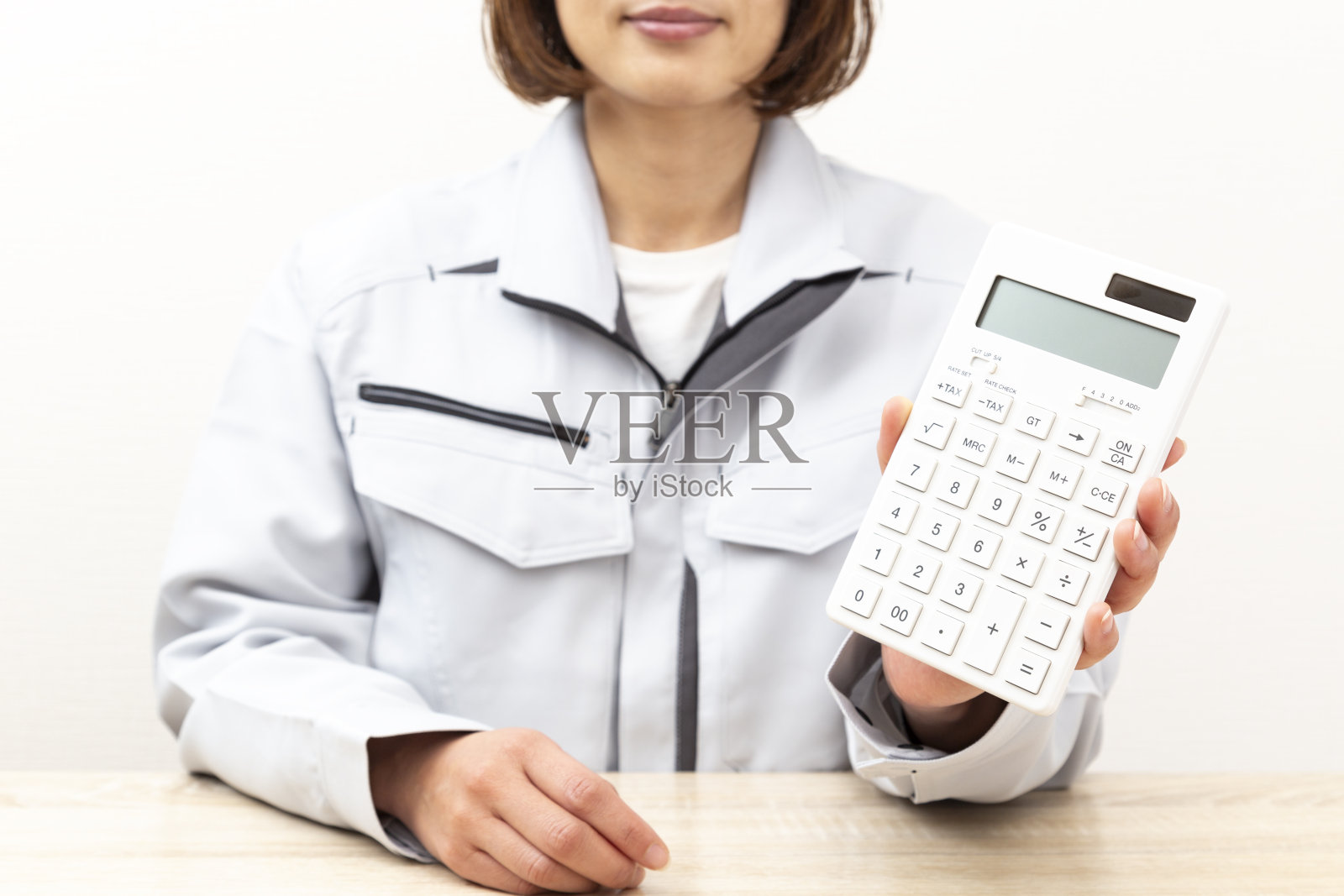 一个穿着工作服拿着计算器的女人。照片摄影图片