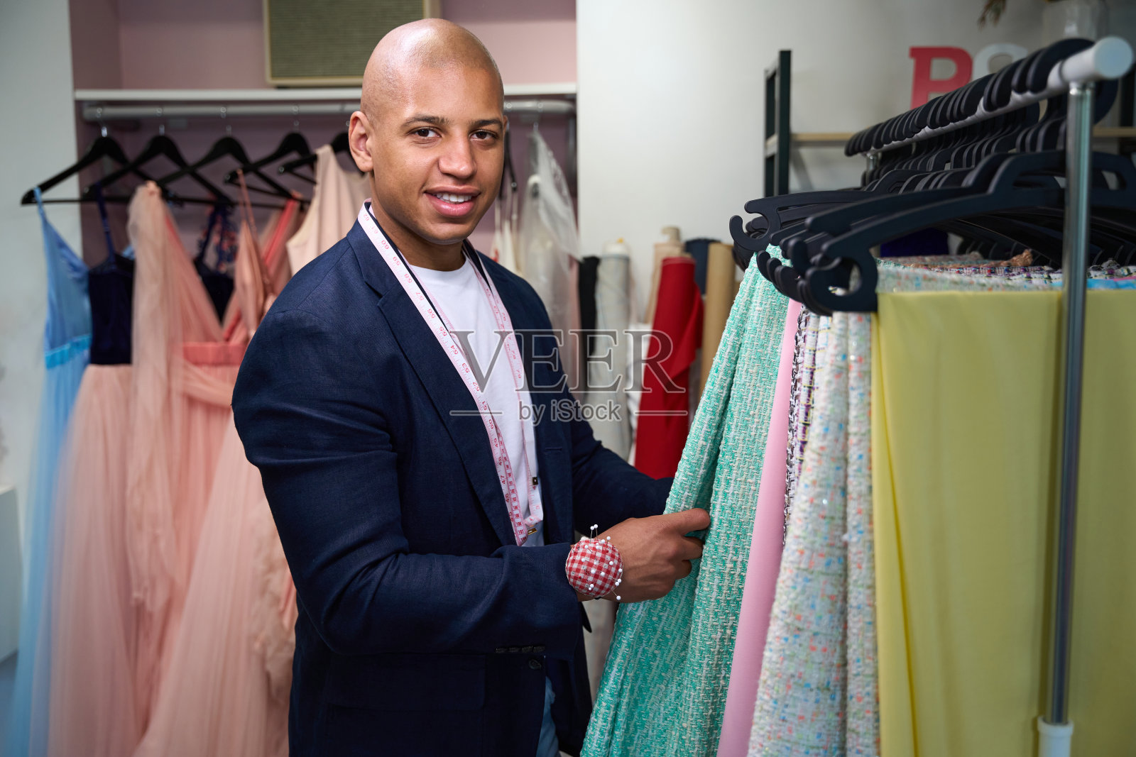 快乐的裁缝在他的缝纫车间里选择衣服的材料照片摄影图片