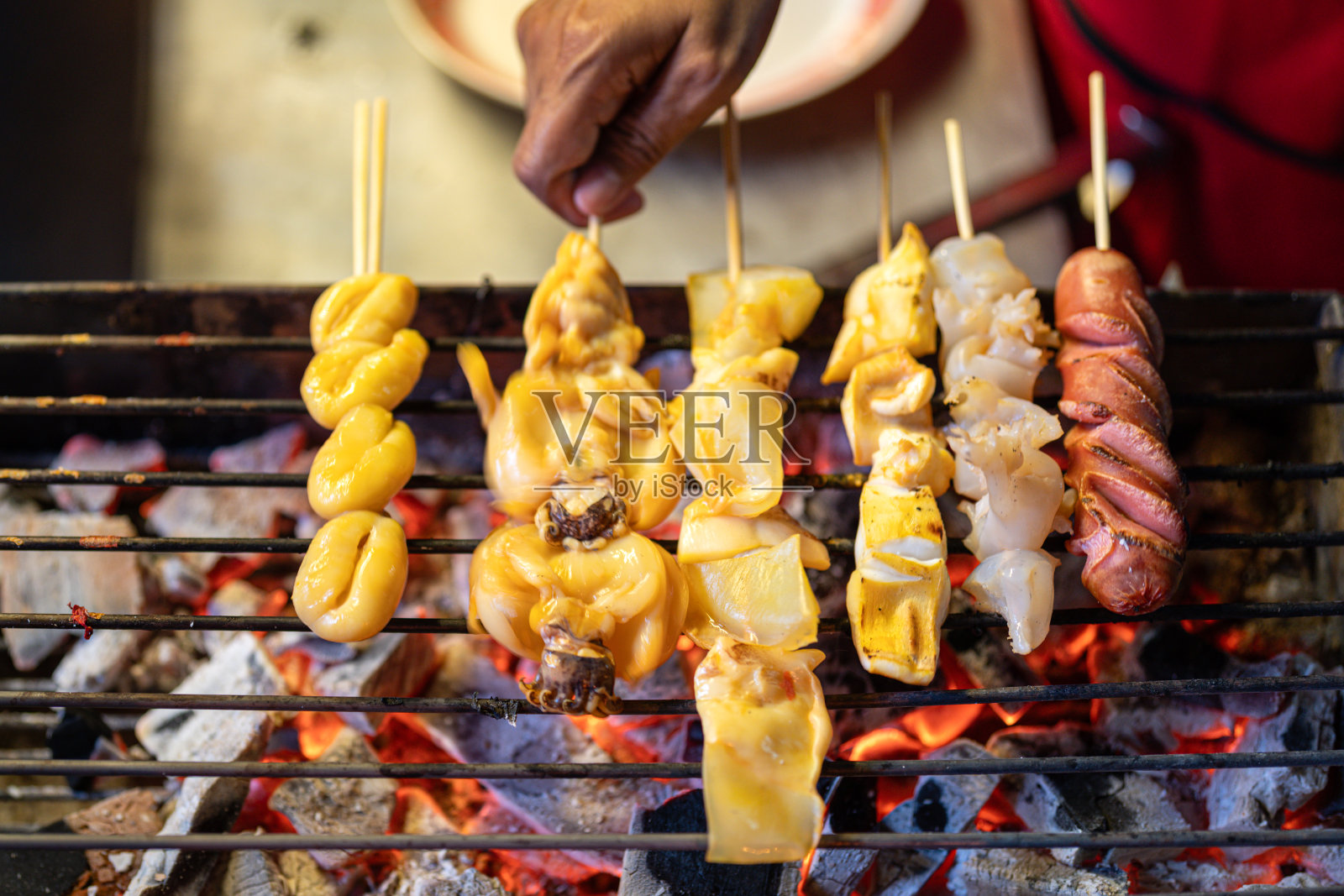 新鲜的鱿鱼、香肠和肉丸正在炭炉上熊熊地烤着照片摄影图片