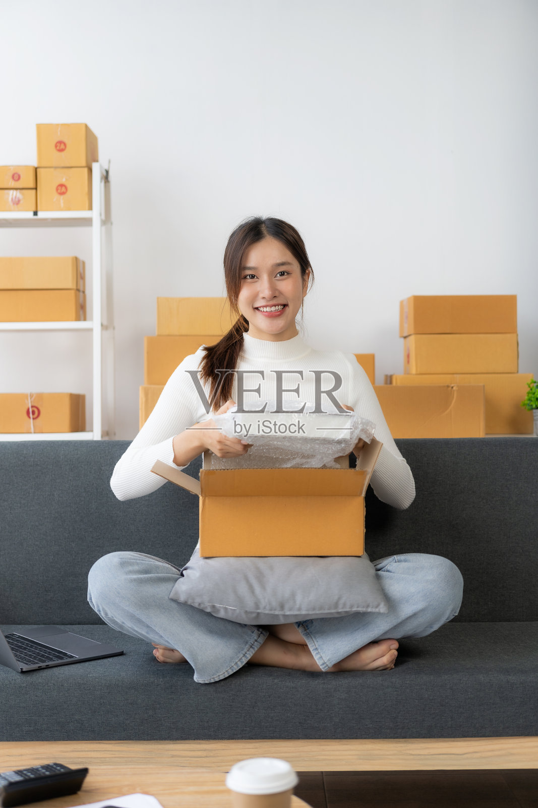 开始做小生意，中小企业的业务为网上卖家独立的亚洲女孩使用电脑和接受订单包装产品交付给客户。交付的概念。垂直的图像。照片摄影图片