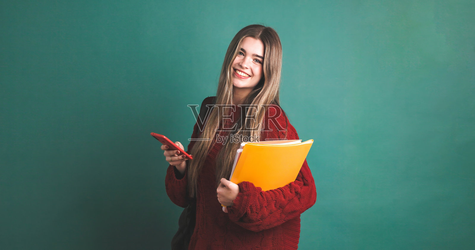 快乐的女大学生拿着书和智能手机照片摄影图片