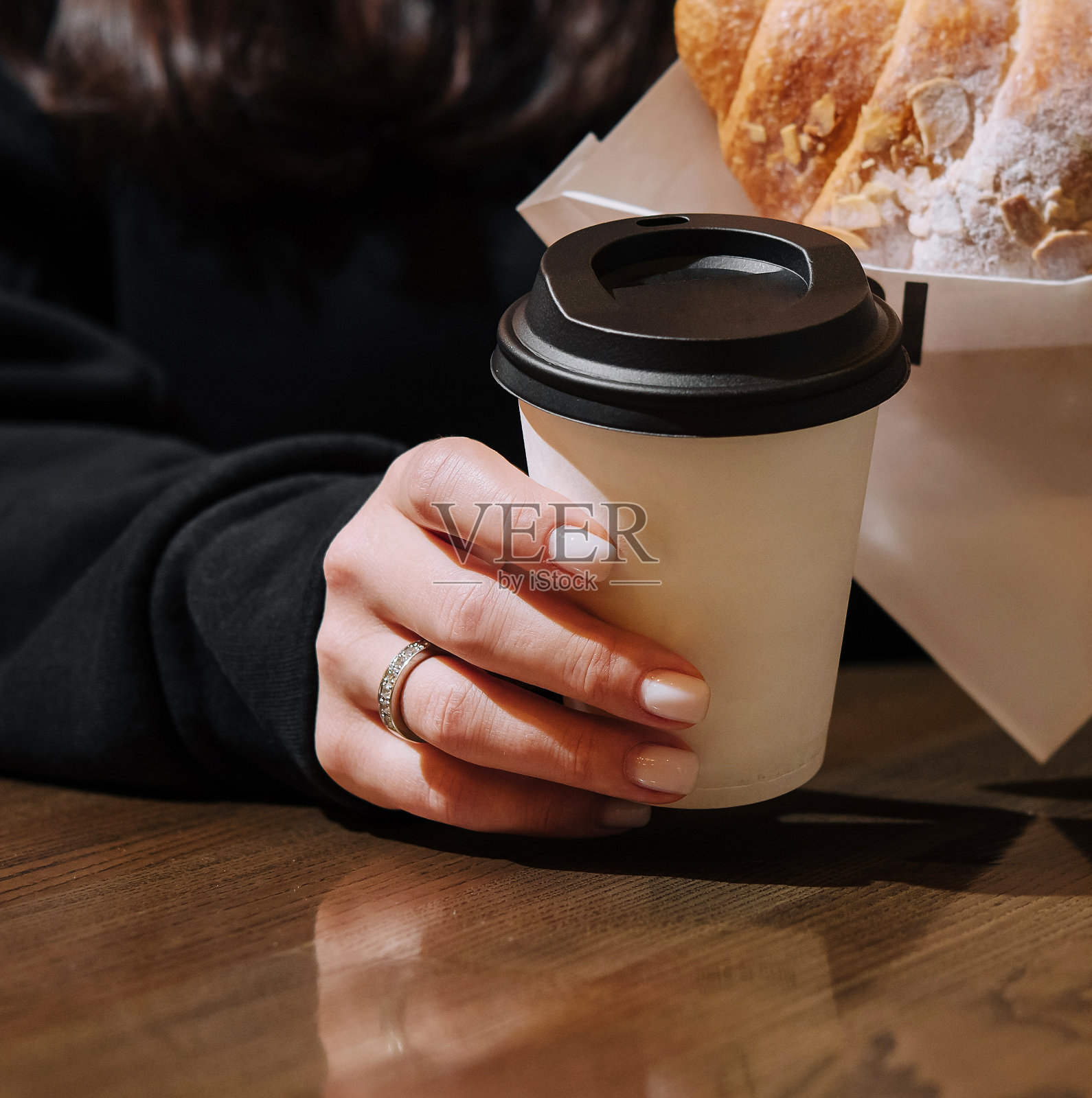 拿着一杯咖啡和一个羊角面包的女人照片摄影图片