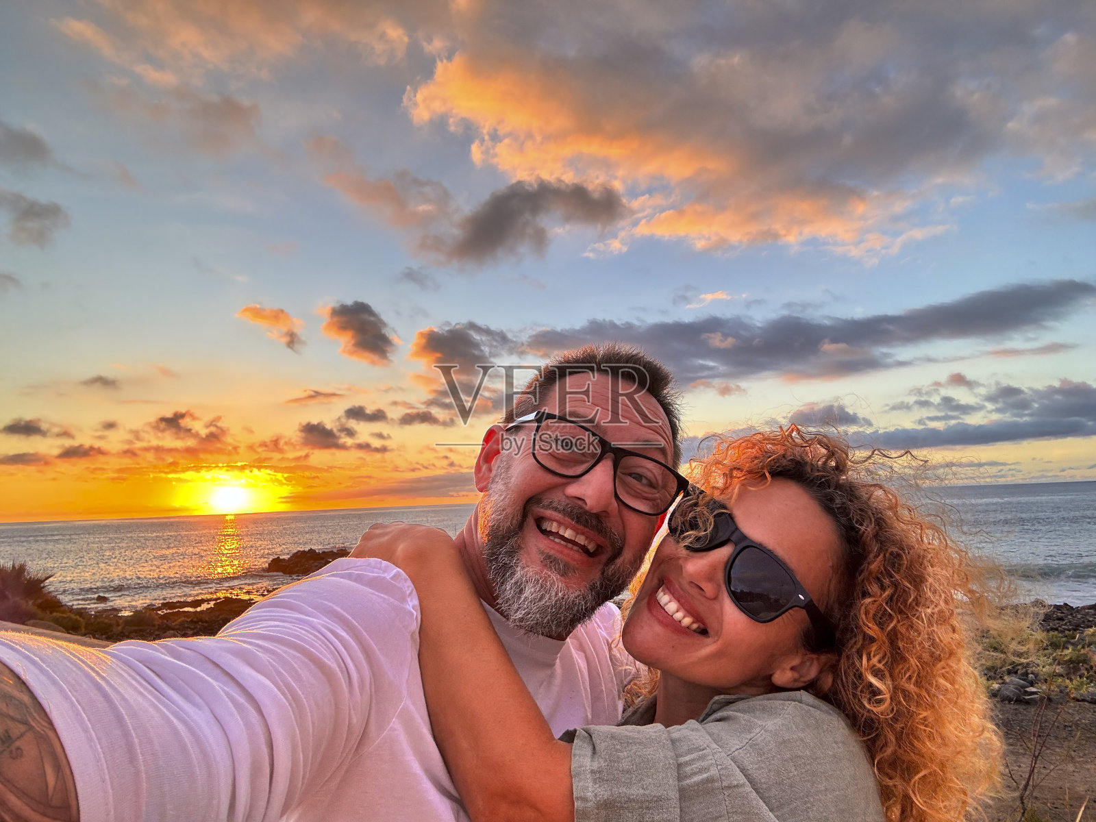 幸福的成年夫妇在爱情自拍与浪漫美妙的日落在海洋的背景。年轻成熟的男女享受旅游目的地在暑假假期照片摄影图片