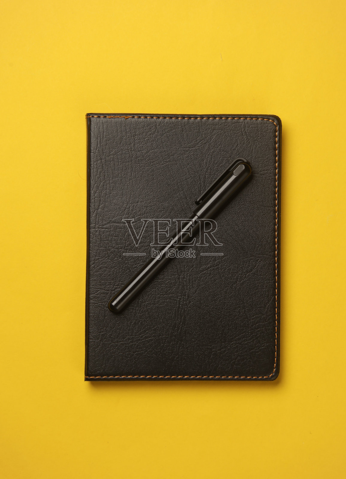 笔记本与黑色皮革封面和黄色背景笔照片摄影图片