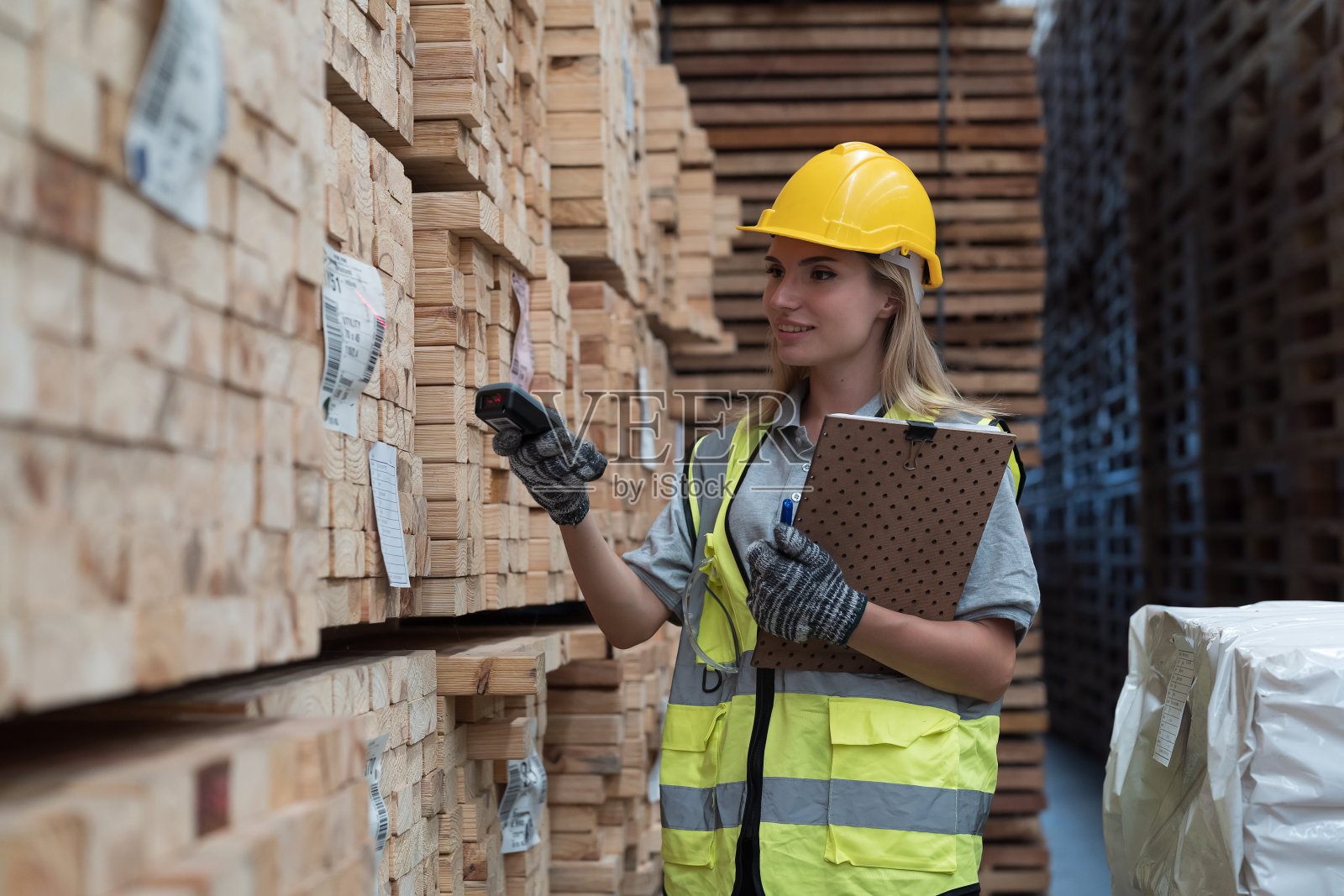 女仓库工人在木材仓库扫描木桩上的条形码。女工在木仓库检查木板上的条形码照片摄影图片