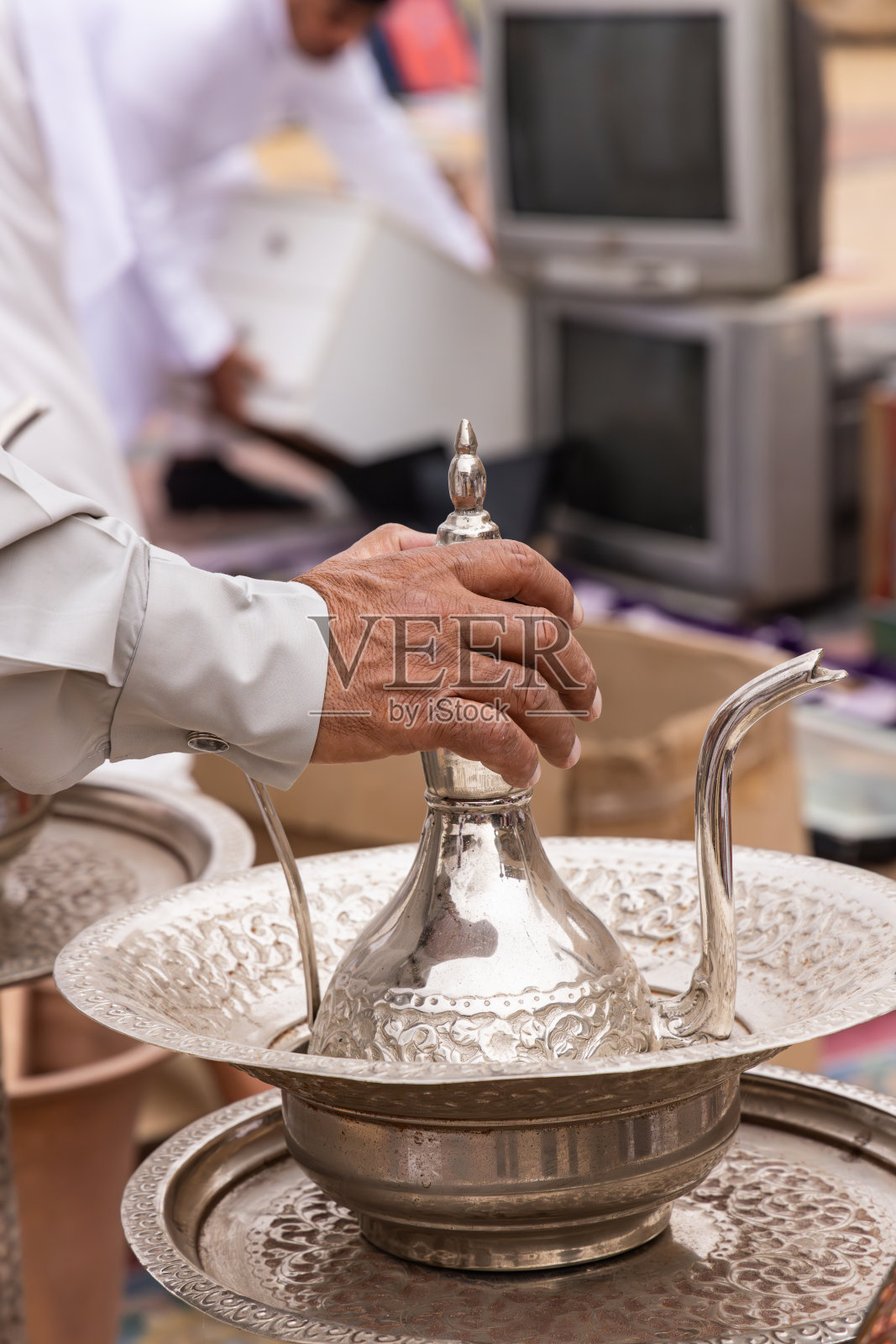 扎尔集市上，一名男子手持银茶壶。照片摄影图片