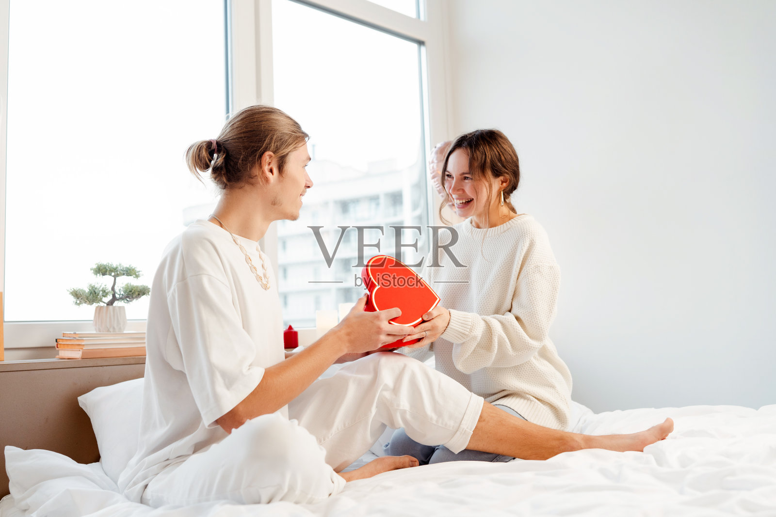 男人给女人送红色礼物。夫妻俩舒舒服服地坐着庆祝节日。情人节照片摄影图片