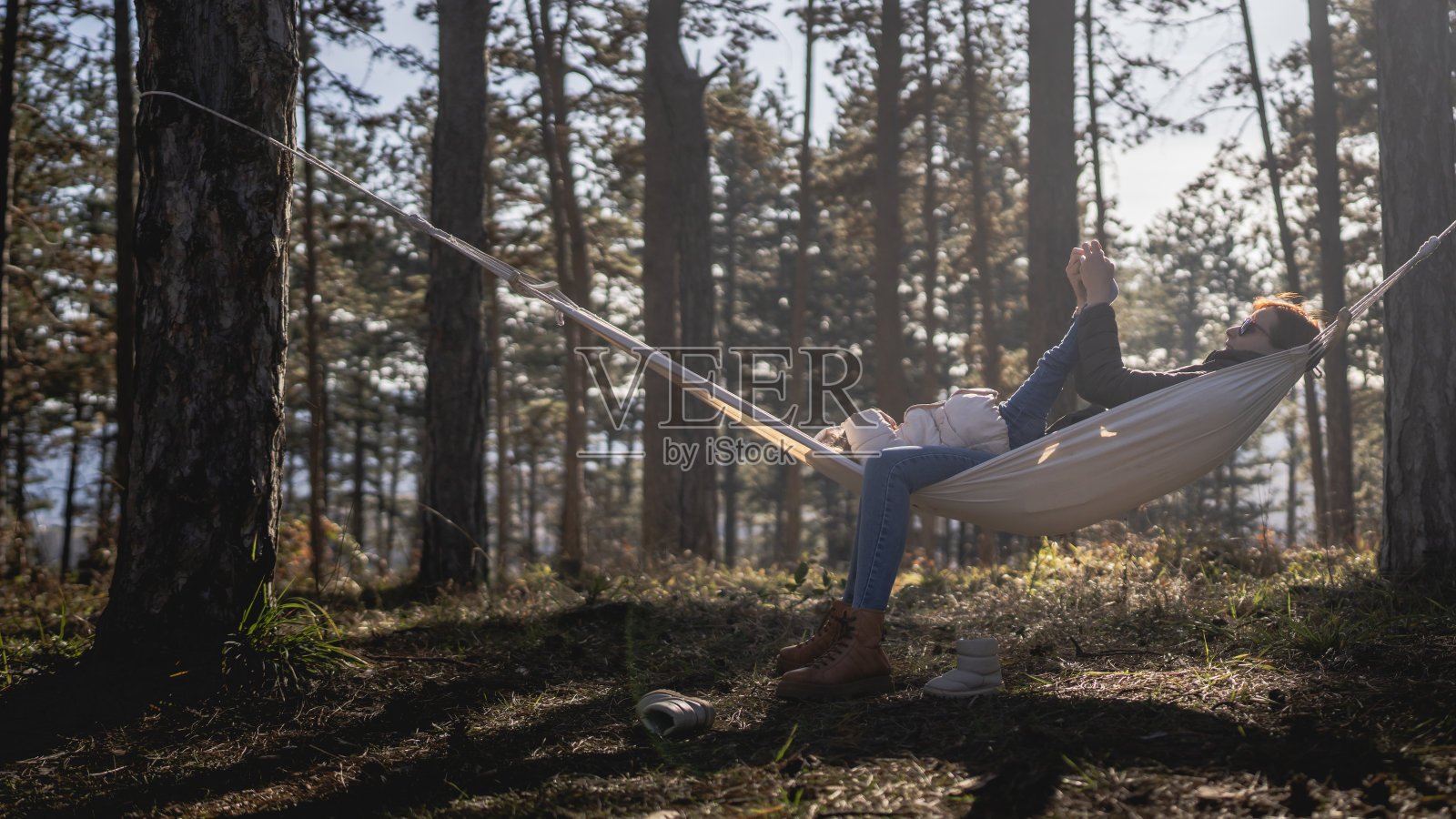 白种人母亲和她的女儿小女孩在大自然的吊床上在冬天或春天阳光明媚的日子里放松和享受照片摄影图片