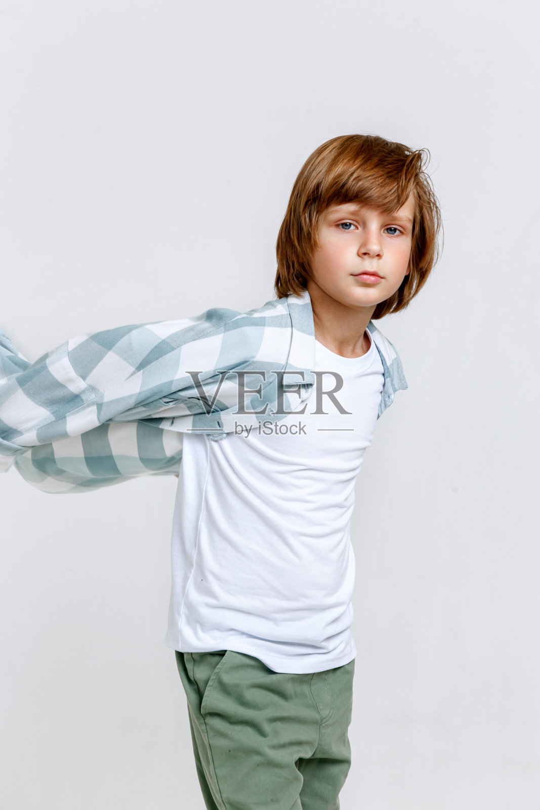 时尚的小男孩模特穿着绿色格子衬衫和白色t恤，在白色的工作室背景上摆姿势照片摄影图片
