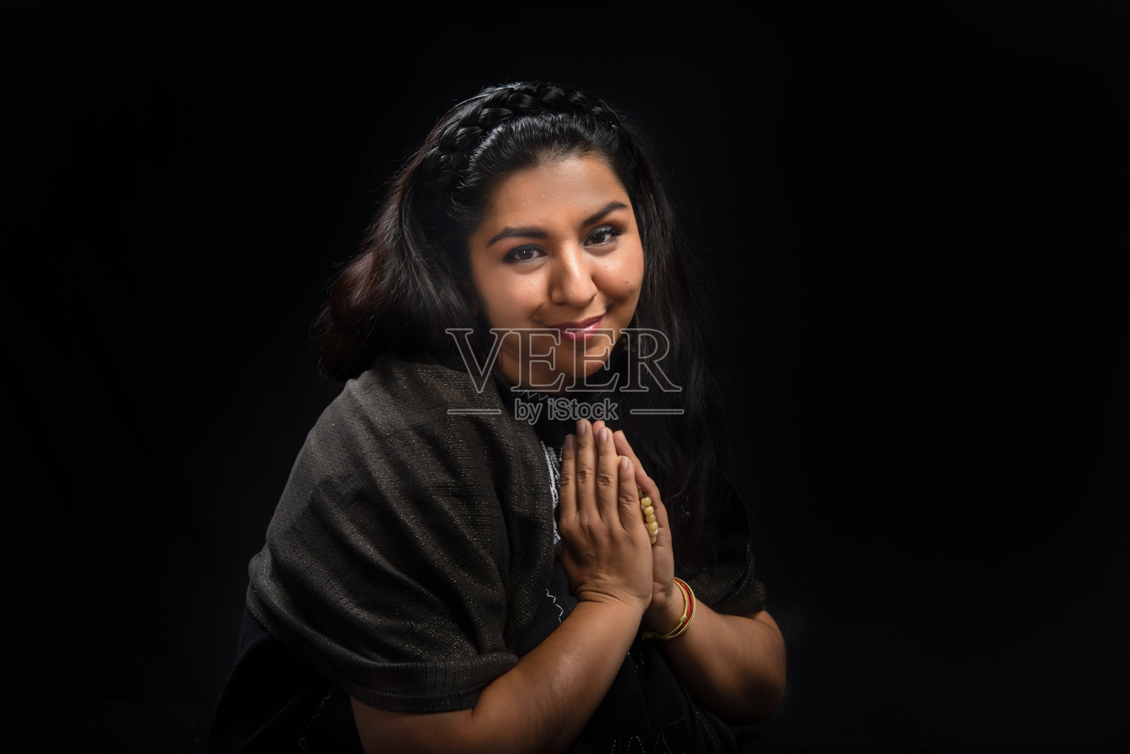 精神上的宁静:一个棕色皮肤、黑色头发的拉丁女人坐在黑色背景下的垫子上，进行能量净化。照片摄影图片