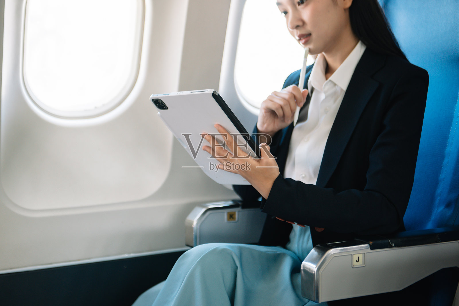 商业女性坐在平板电脑前，笔记本电脑上有财务图表和统计数据照片摄影图片