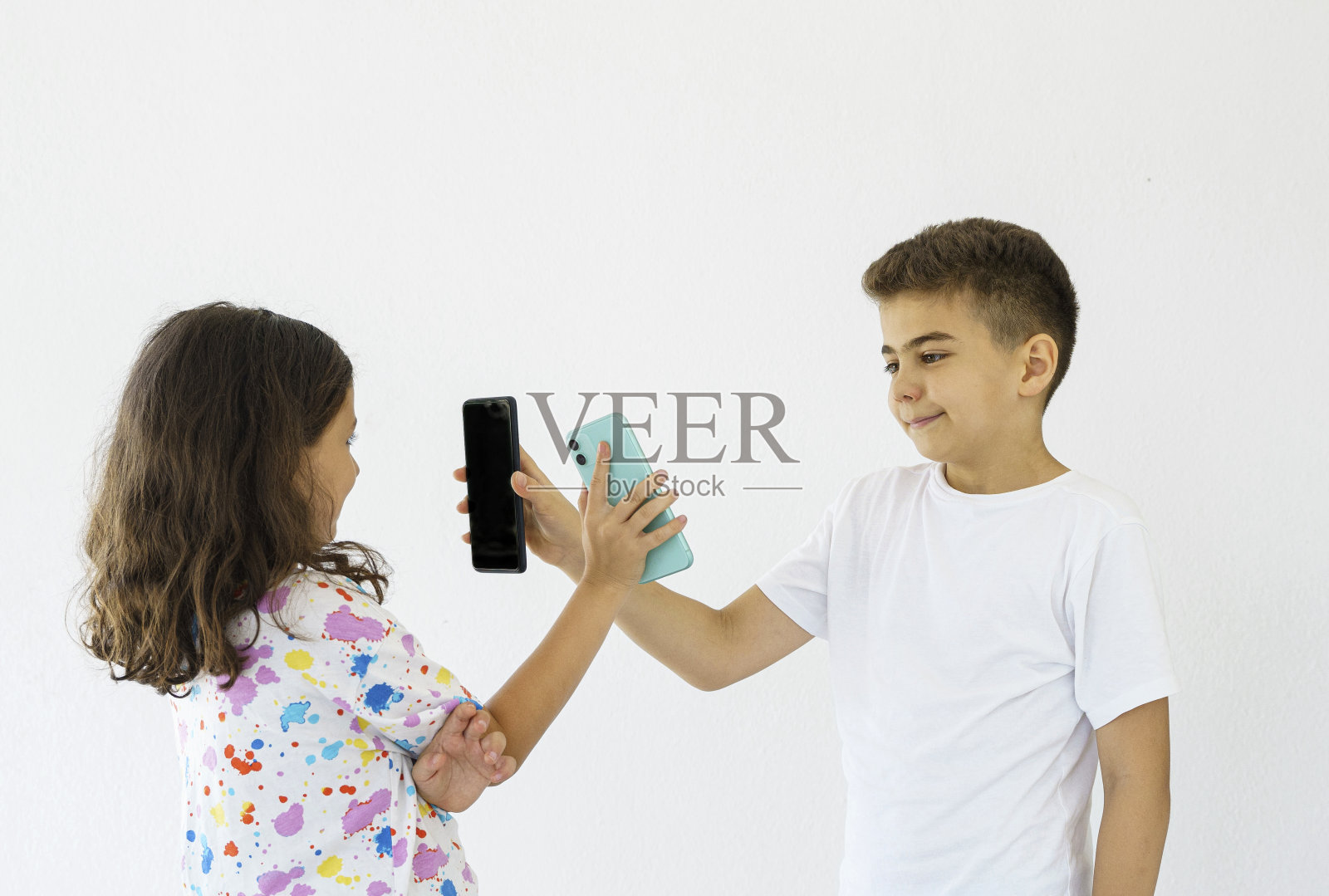 可爱的小兄弟姐妹在白色的墙壁背景上玩或看视频照片摄影图片