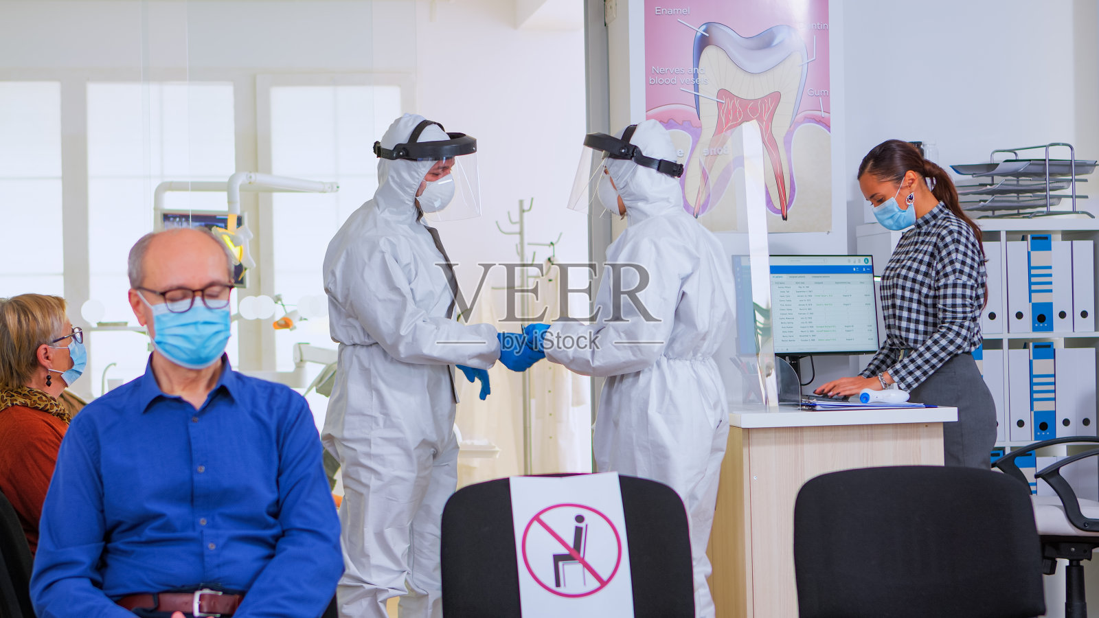 穿着防护服的牙科医生在接待处分析牙齿x光片照片摄影图片