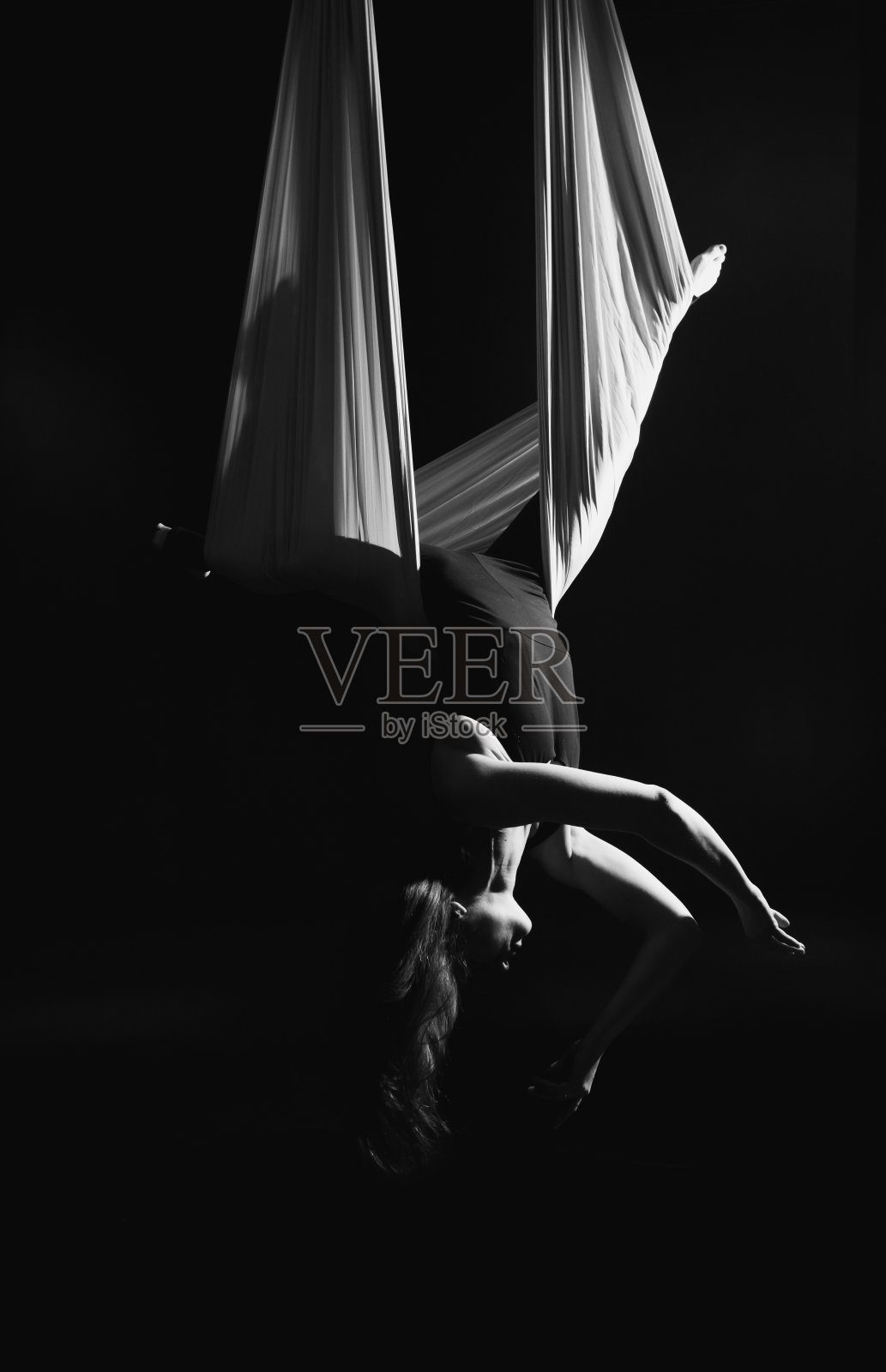 飞瑜伽。黑底白色吊床上的女孩正在表演空中杂技。体操，马戏，穹顶下。光影的发挥营造出戏剧表演的感觉。体育活动照片摄影图片