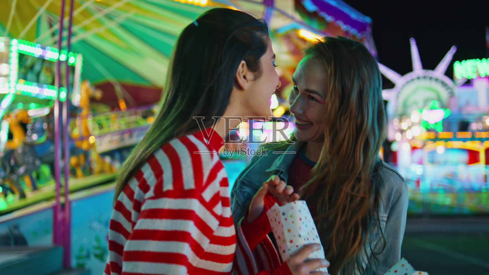 快乐的女孩在月亮游乐园谈论分享秘密。快乐的好朋友照片摄影图片