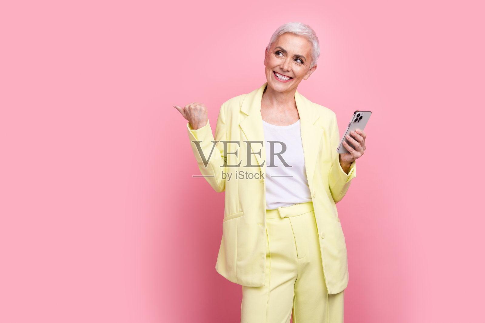 成功的女商人的照片，西装，手指空白的空间，使用智能手机应用程序规划孤立的粉红色背景照片摄影图片