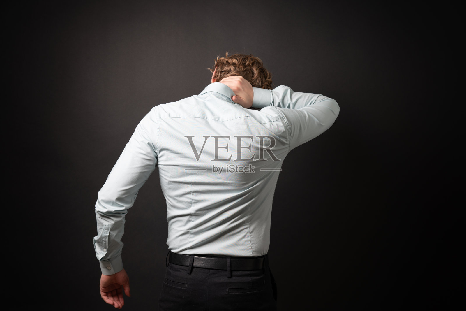 穿着办公室装的商人因工作姿势不当而脖子疼痛。照片摄影图片