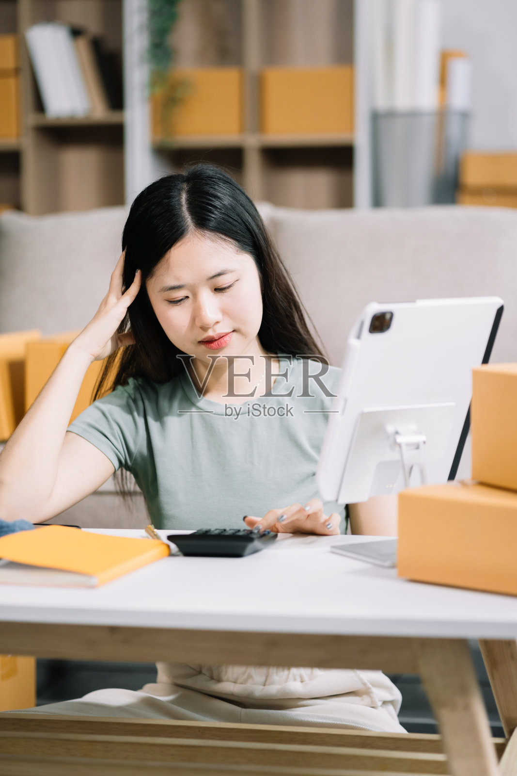 压力女商人坐在桌子上，承受着来自网上卖家工作的压力。照片摄影图片