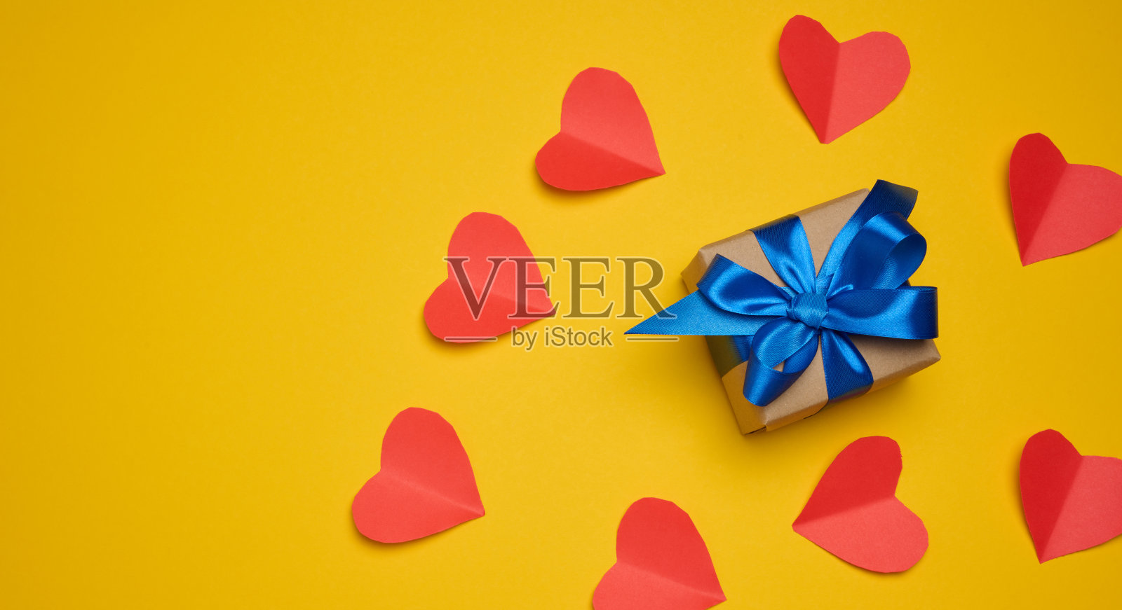 礼盒与红色缎带和蝴蝶结在一个黄色的背景。节日的背景照片摄影图片