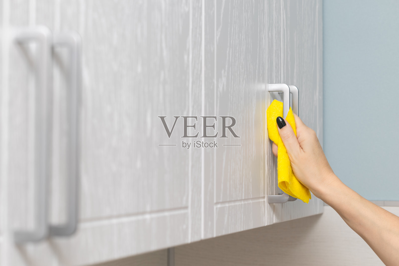 女人用抹布擦拭厨房橱柜。照片摄影图片