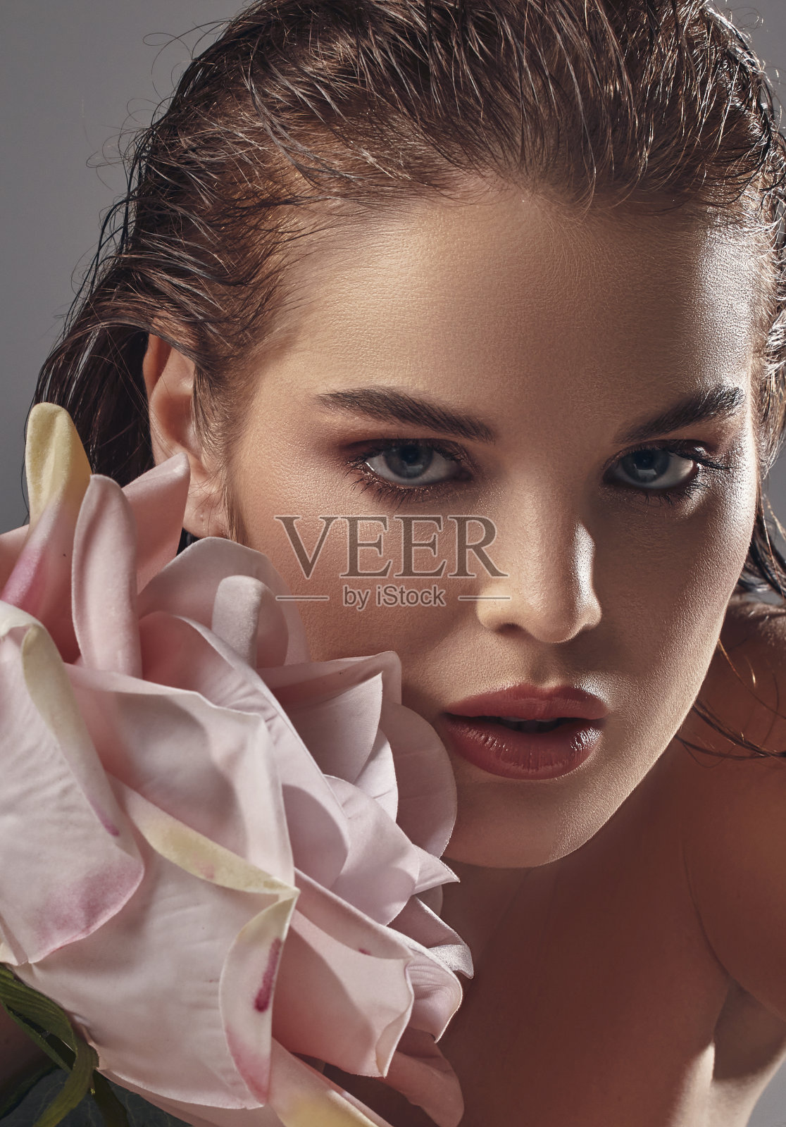 一个美丽的女人，脸颊上有一朵大玫瑰。照片摄影图片