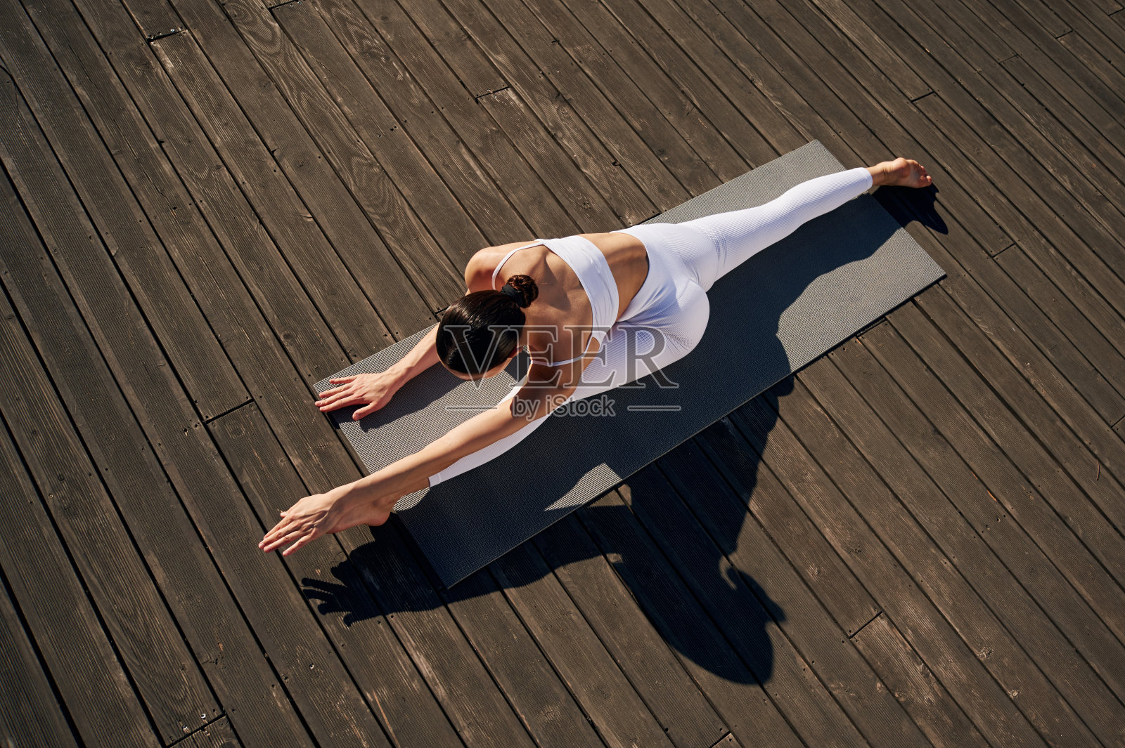 伸展双腿。穿着健身服的年轻女子在户外照片摄影图片