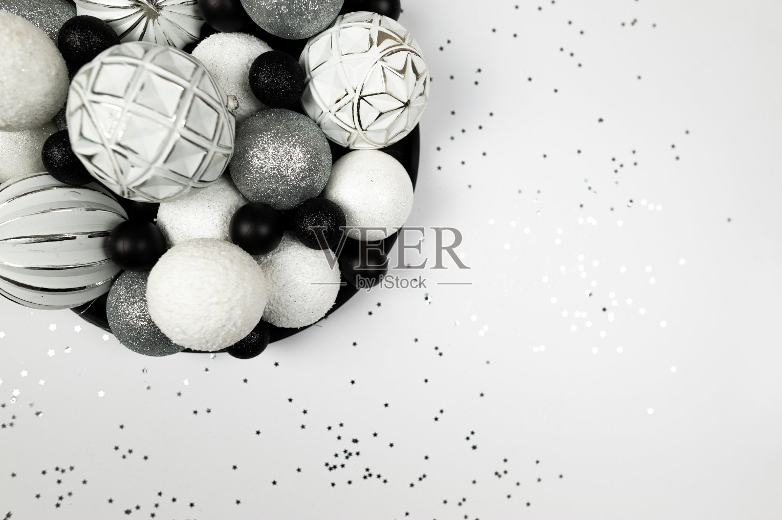 圣诞构图，杉树装饰，白色，银色和黑色的小玩意，银星纸屑在白色的背景。照片摄影图片