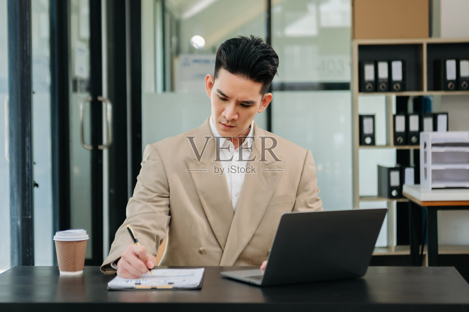 自信的亚洲人带着微笑站在现代办公室拿着笔记本和平板电脑。照片摄影图片