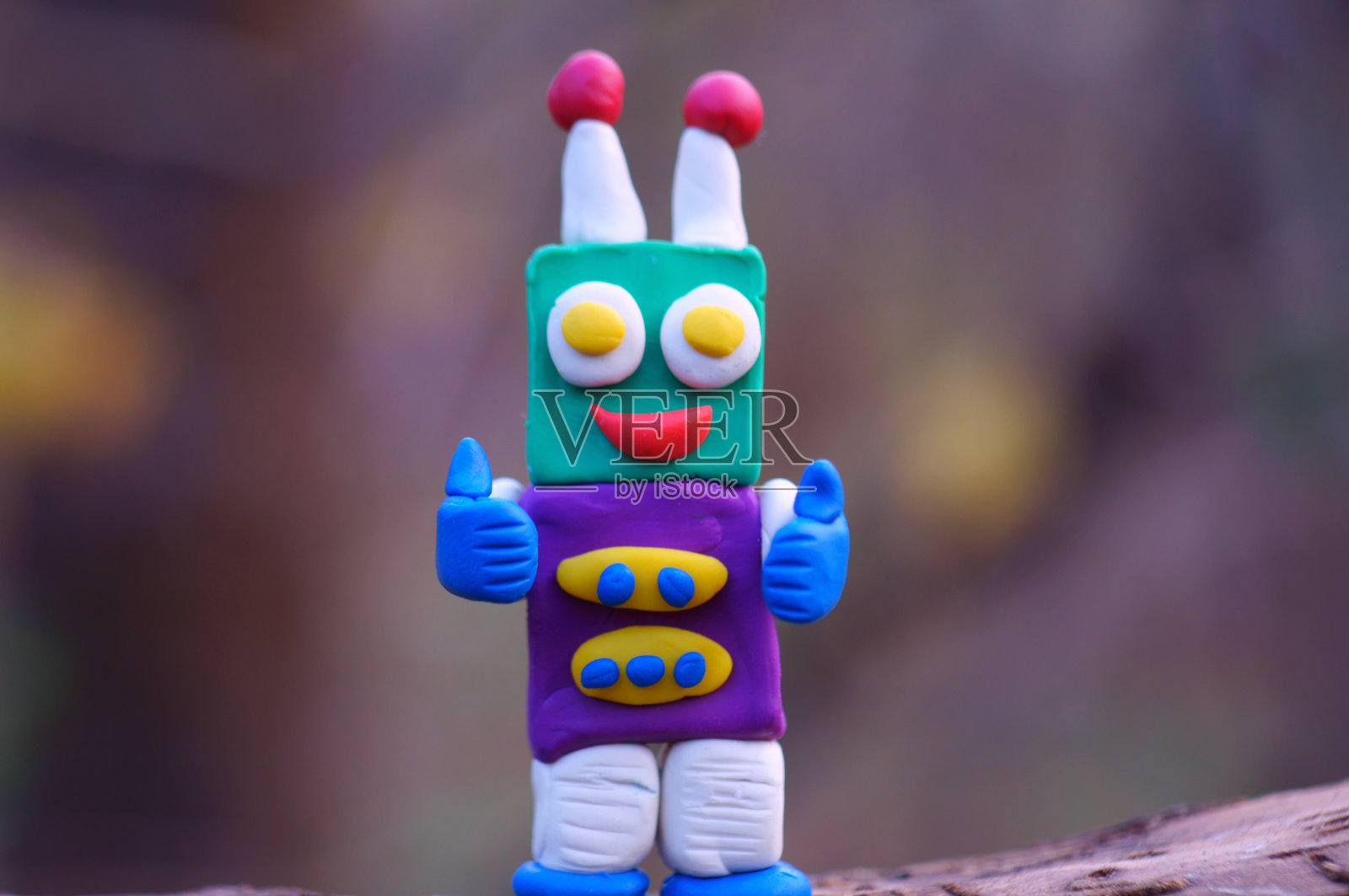 一个用橡皮泥做的玩具机器人在微笑。照片摄影图片