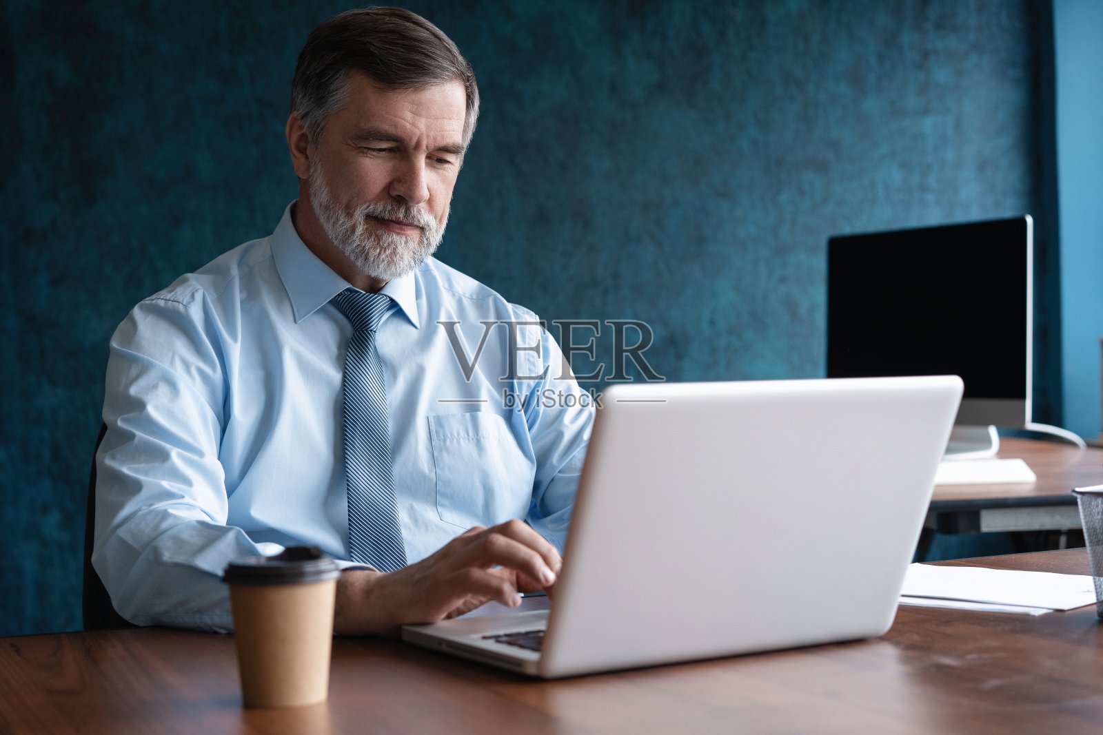 成熟的商人，执行经理，看着笔记本电脑，观看在线网络研讨会培训或进行虚拟会议视频会议，做笔记，做市场调查，在办公室工作。照片摄影图片