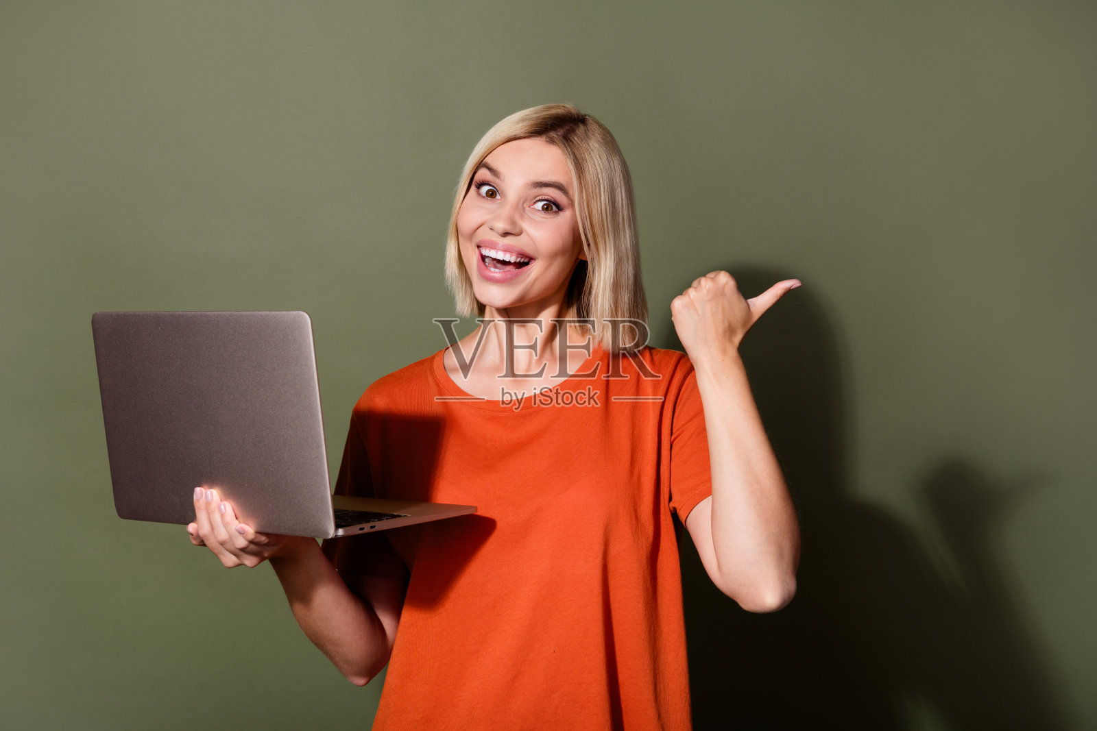 可爱的年轻女士的照片肖像拿着上网本点兴奋的空白空间穿着时髦的橙色服装孤立在卡其色的背景照片摄影图片