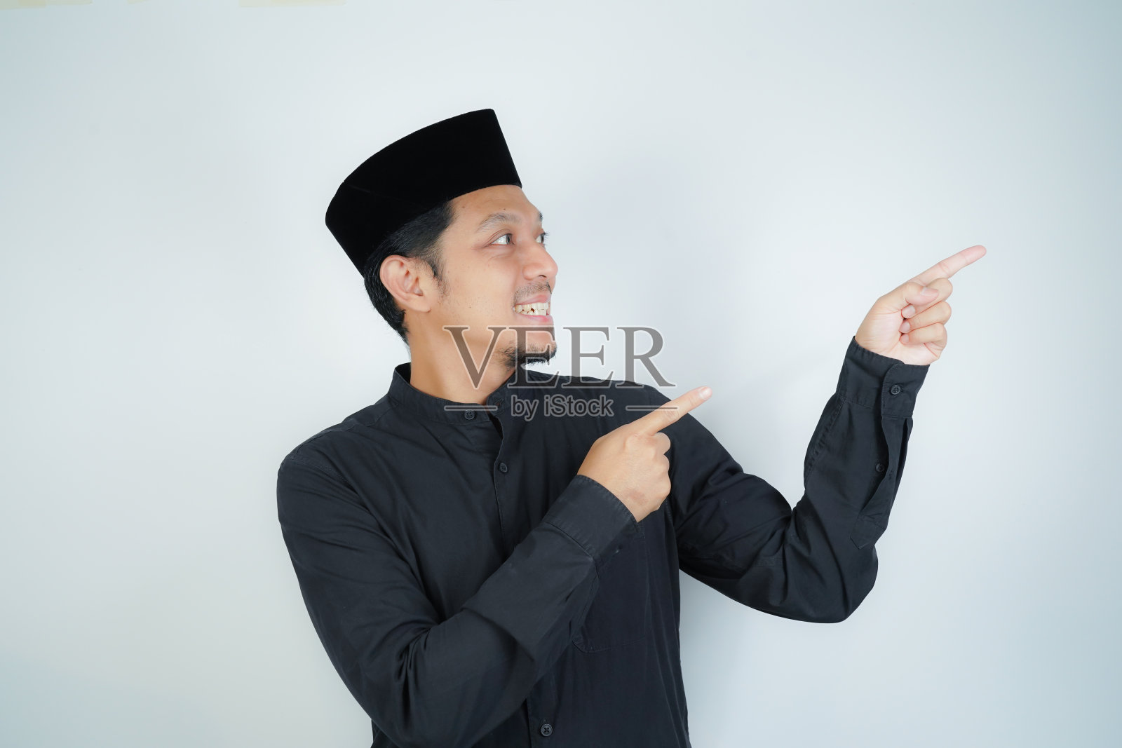 开朗英俊的亚洲穆斯林男子用手指着孤立背景下的广告空地照片摄影图片