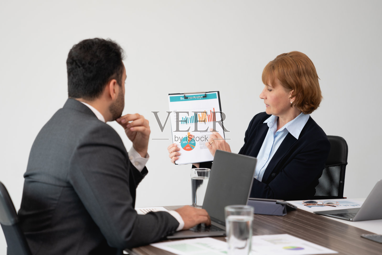 自信的女商人向同事展示会议期间的彩色数据图表照片摄影图片