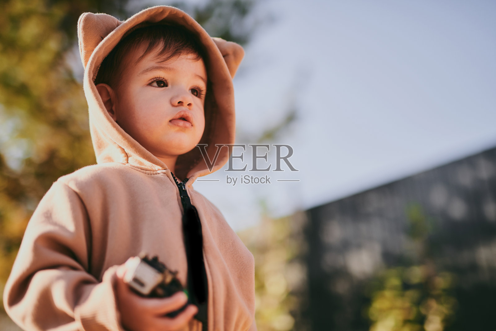 小男孩穿着连帽熊毛绒连体衣的特写肖像。宝宝在外面玩照片摄影图片