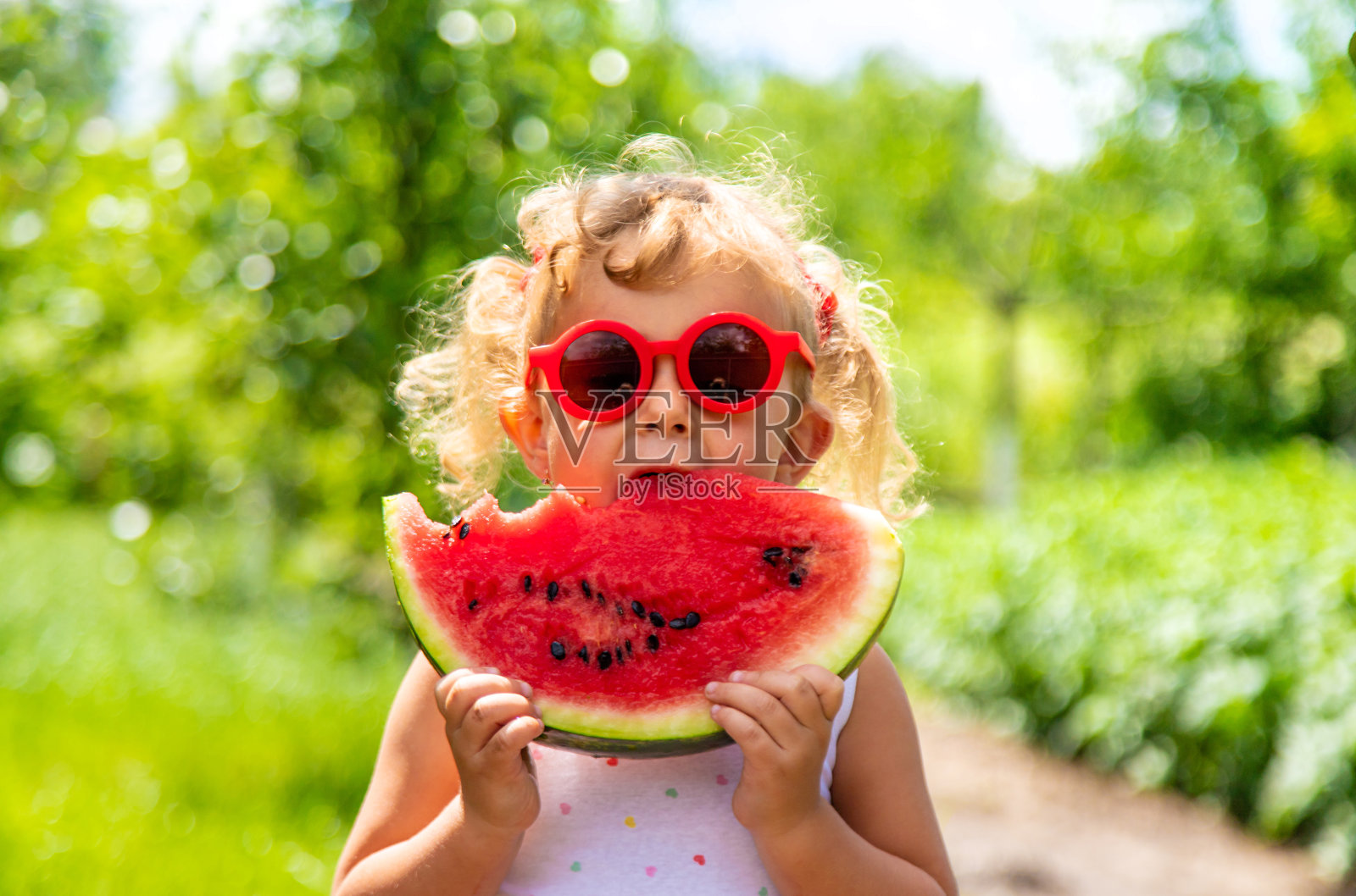 一个孩子在公园里吃西瓜。有选择性的重点。照片摄影图片