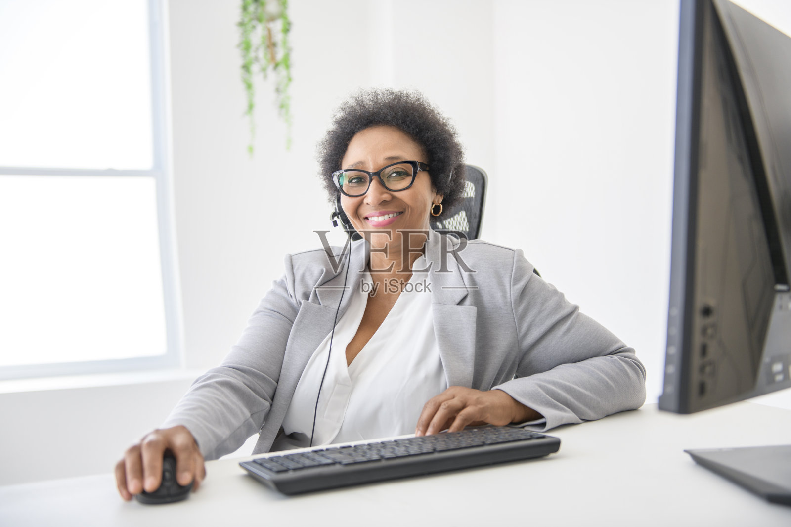 一个黑人女商人坐在办公室里，拿着麦克风和客户说话照片摄影图片