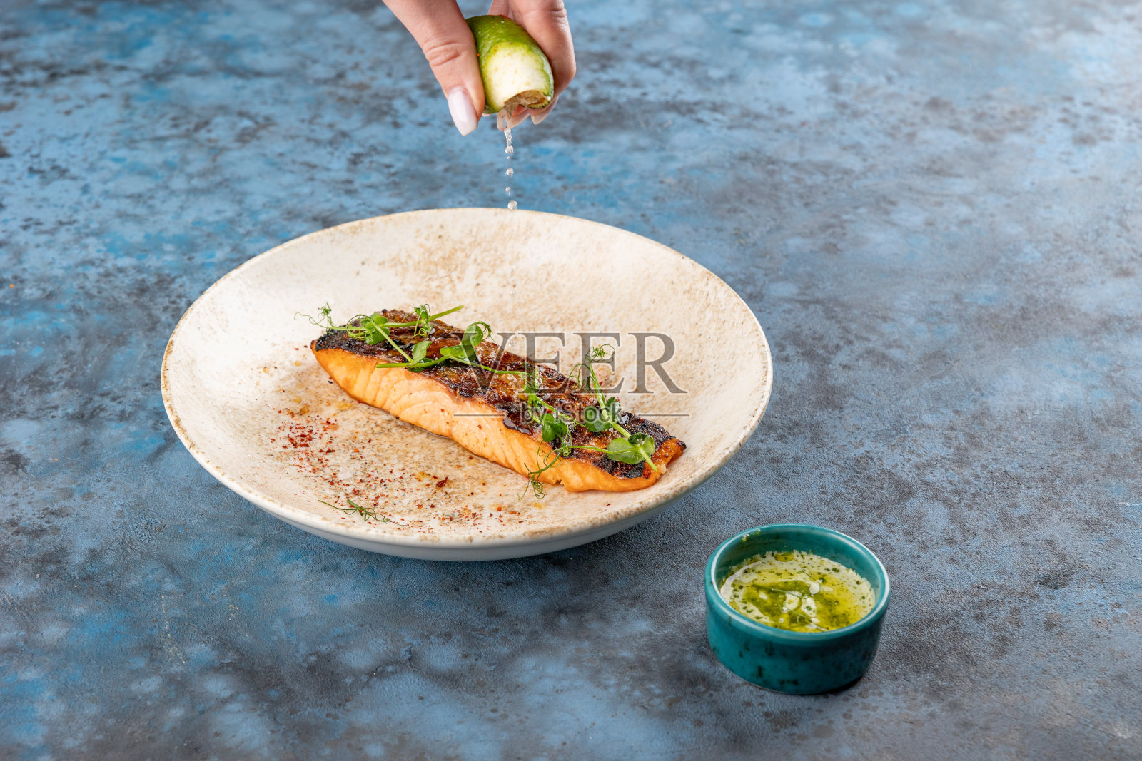 把酸橙挤在烤三文鱼片上。照片摄影图片