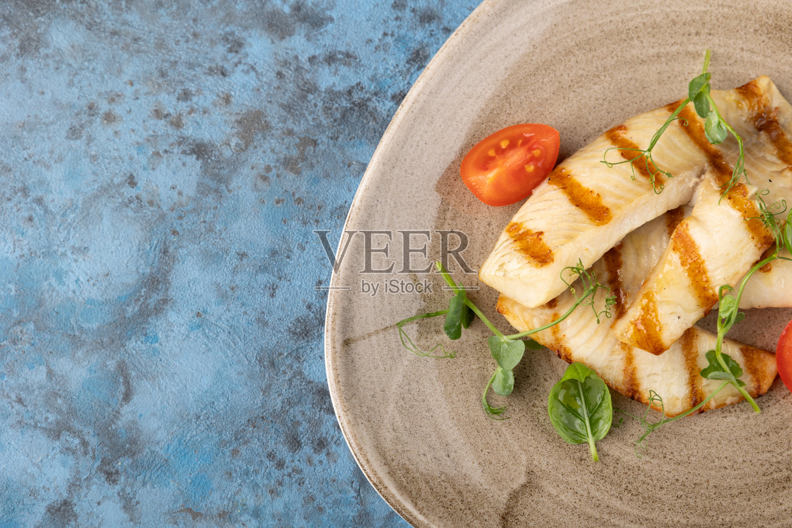 烤白鱼片烧烤。盘子里的西红柿和蔬菜照片摄影图片