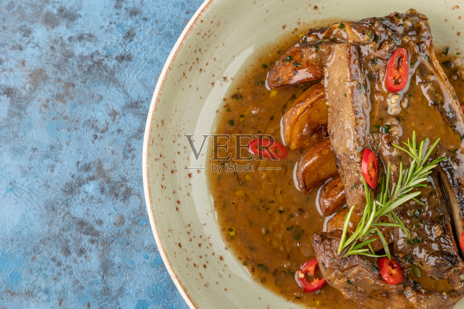 用土豆、迷迭香和辣椒在肉汁里炸肉片照片摄影图片