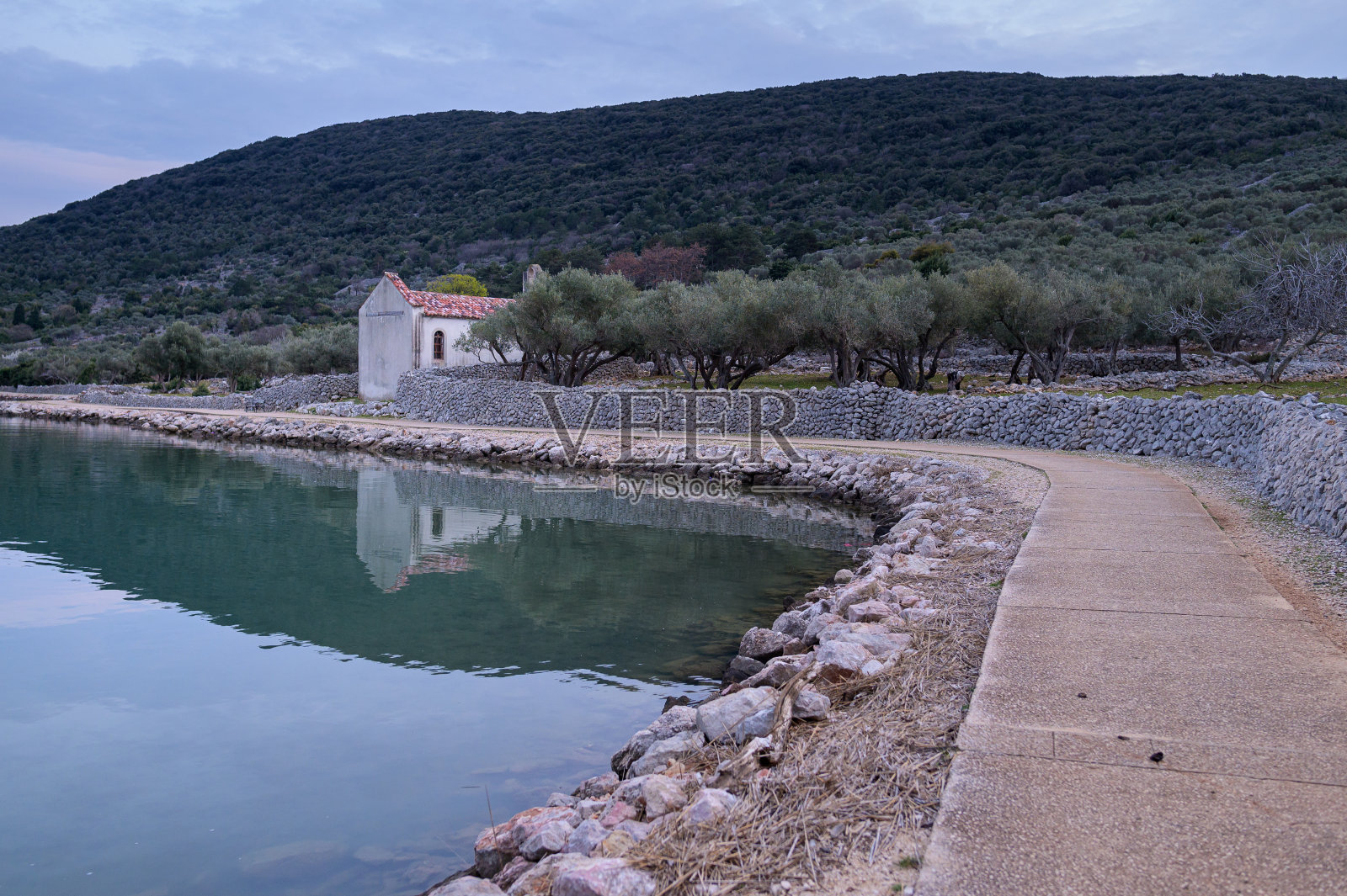 春天日落后，Cres附近的小路、教堂和平静的大海照片摄影图片