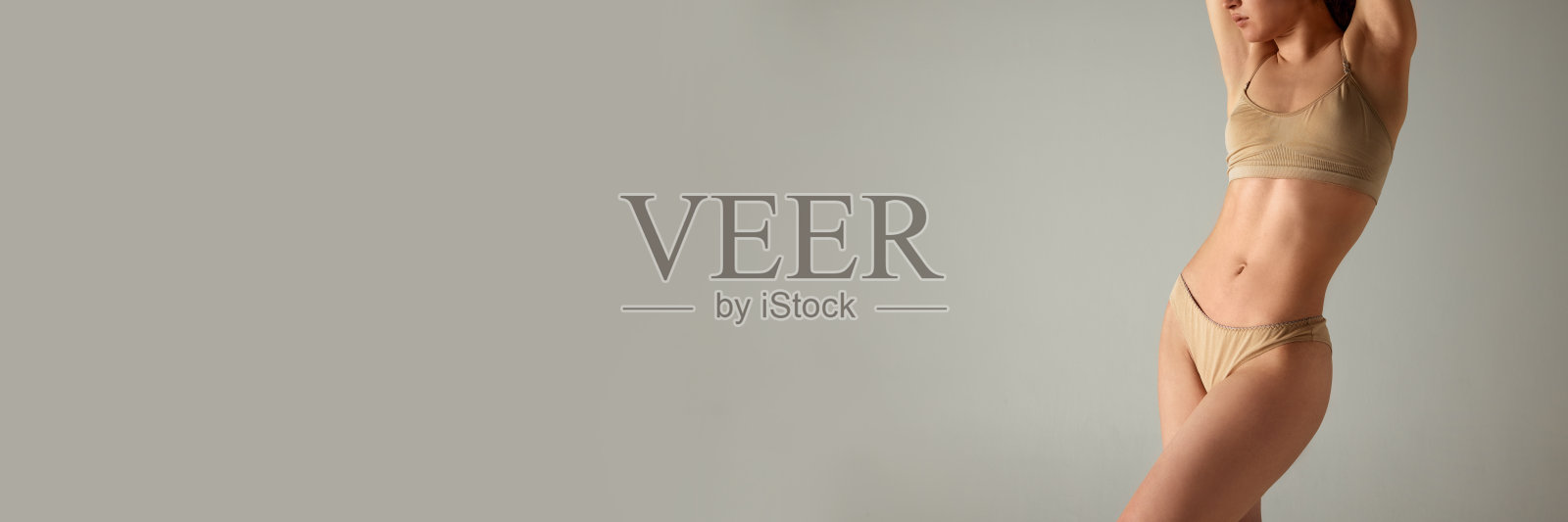 剪裁的形象，温柔，苗条，适合女性的身体。模特穿着内衣在灰色的工作室背景下摆姿势照片摄影图片