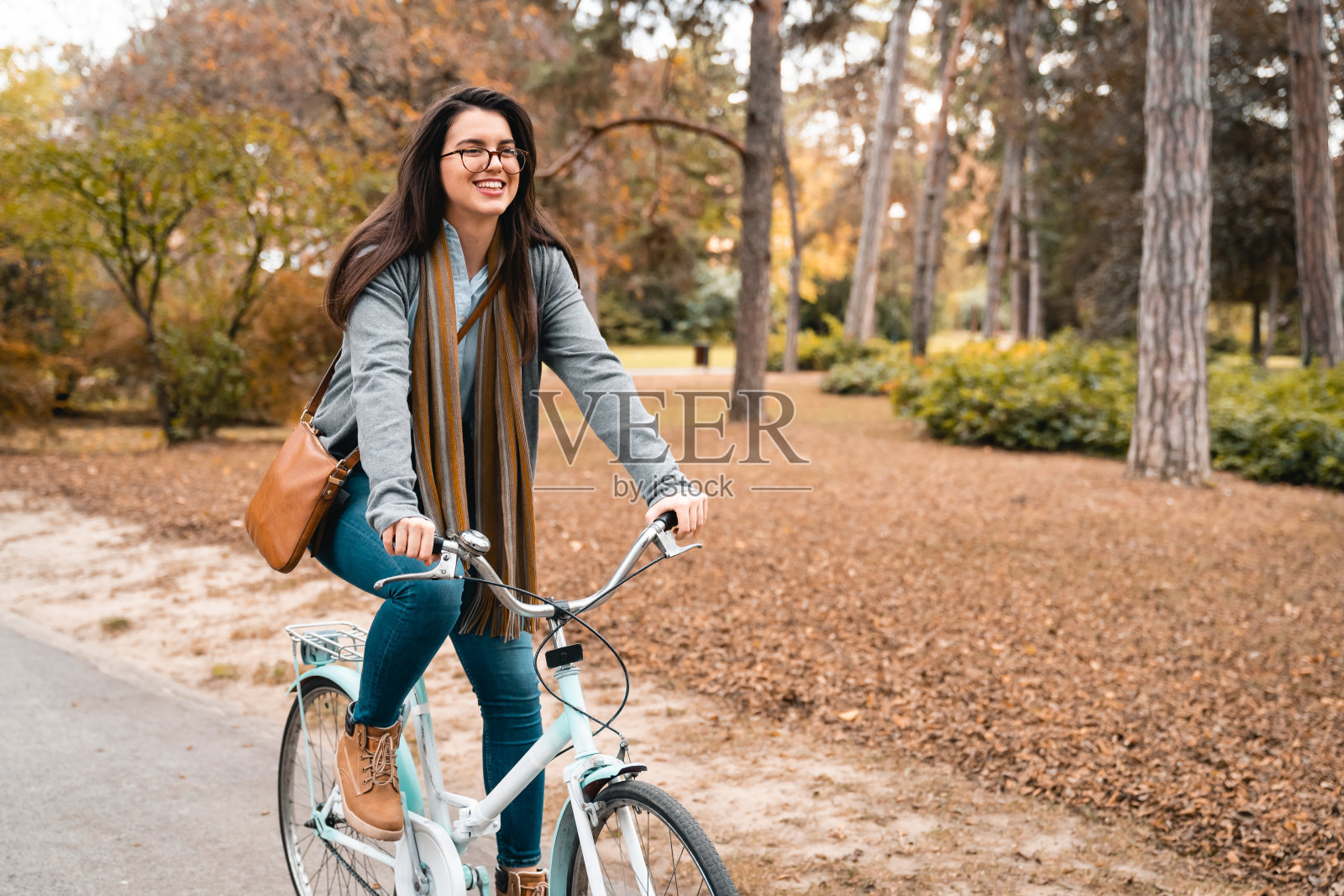 一个放松、快乐的年轻女子在城市公园里骑自行车照片摄影图片