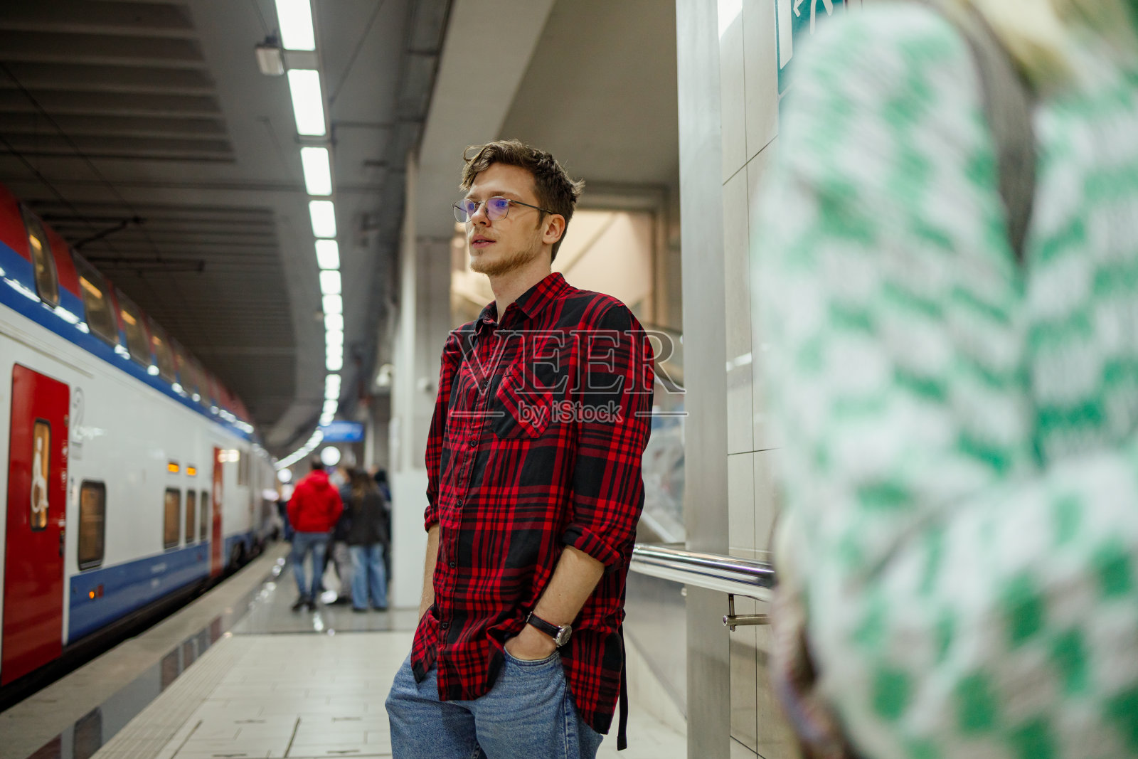 一位乘客站在地铁站候车。照片摄影图片