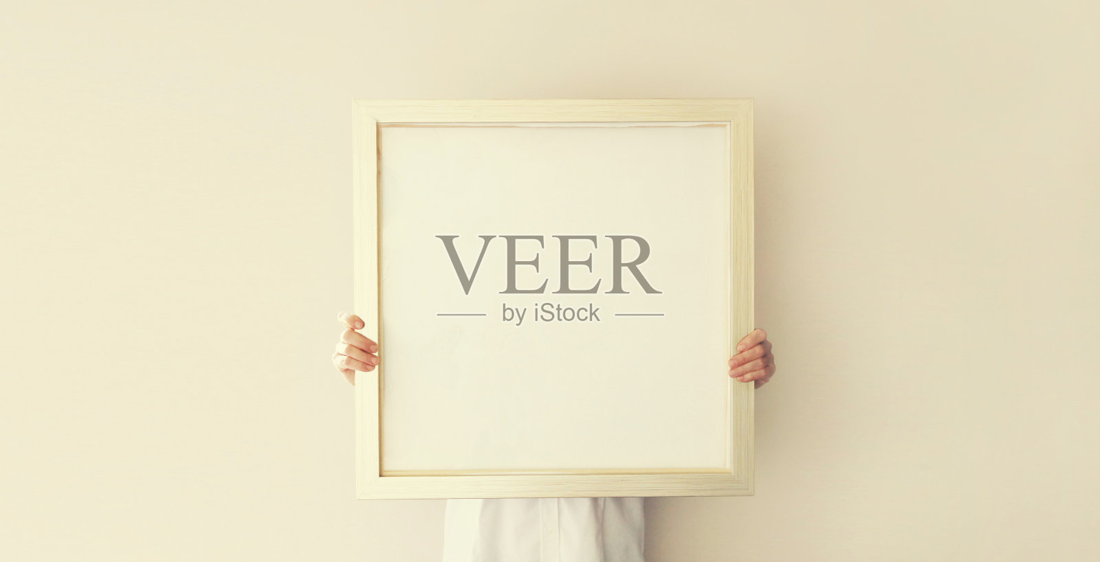 装修室内的女人，在新房的墙上挂着白色的空白相框和木画照片摄影图片