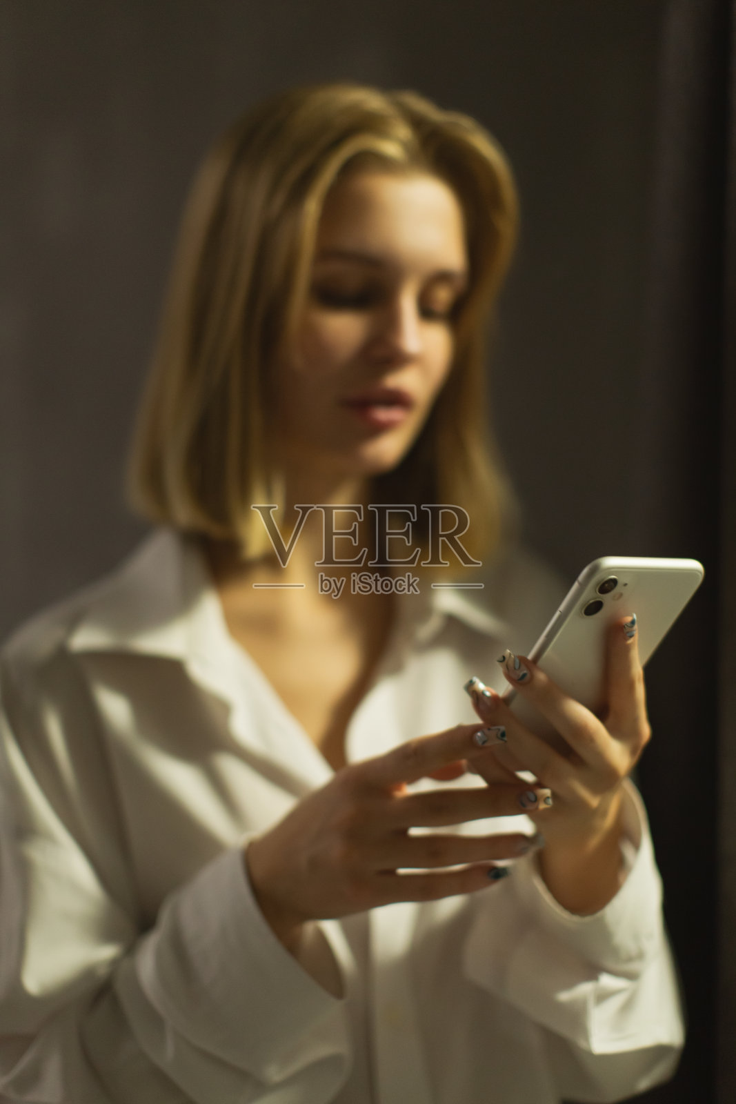 手里拿着手机的金发女人。照片摄影图片