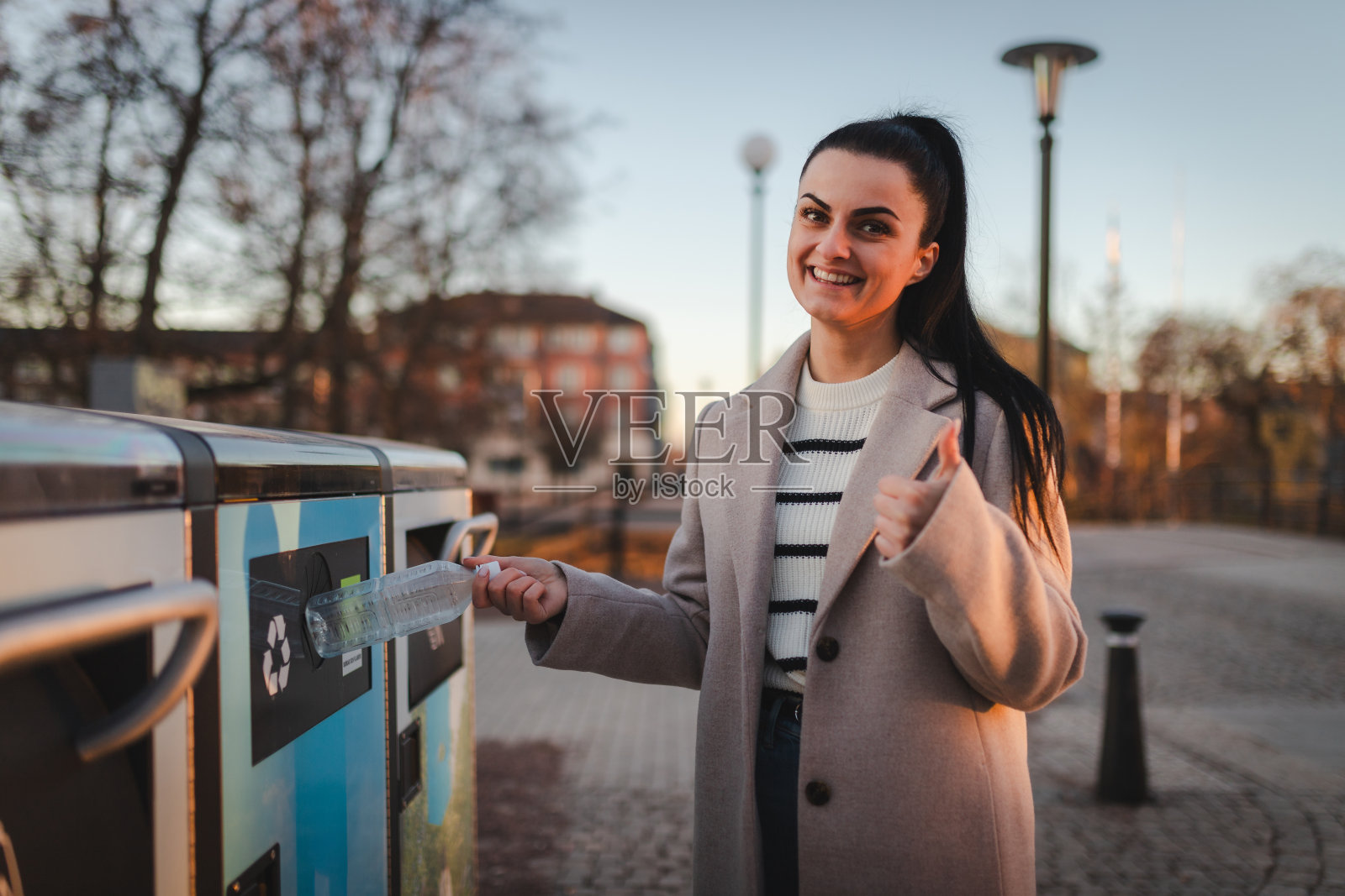 一个微笑的女人在回收时竖起大拇指的肖像照片摄影图片
